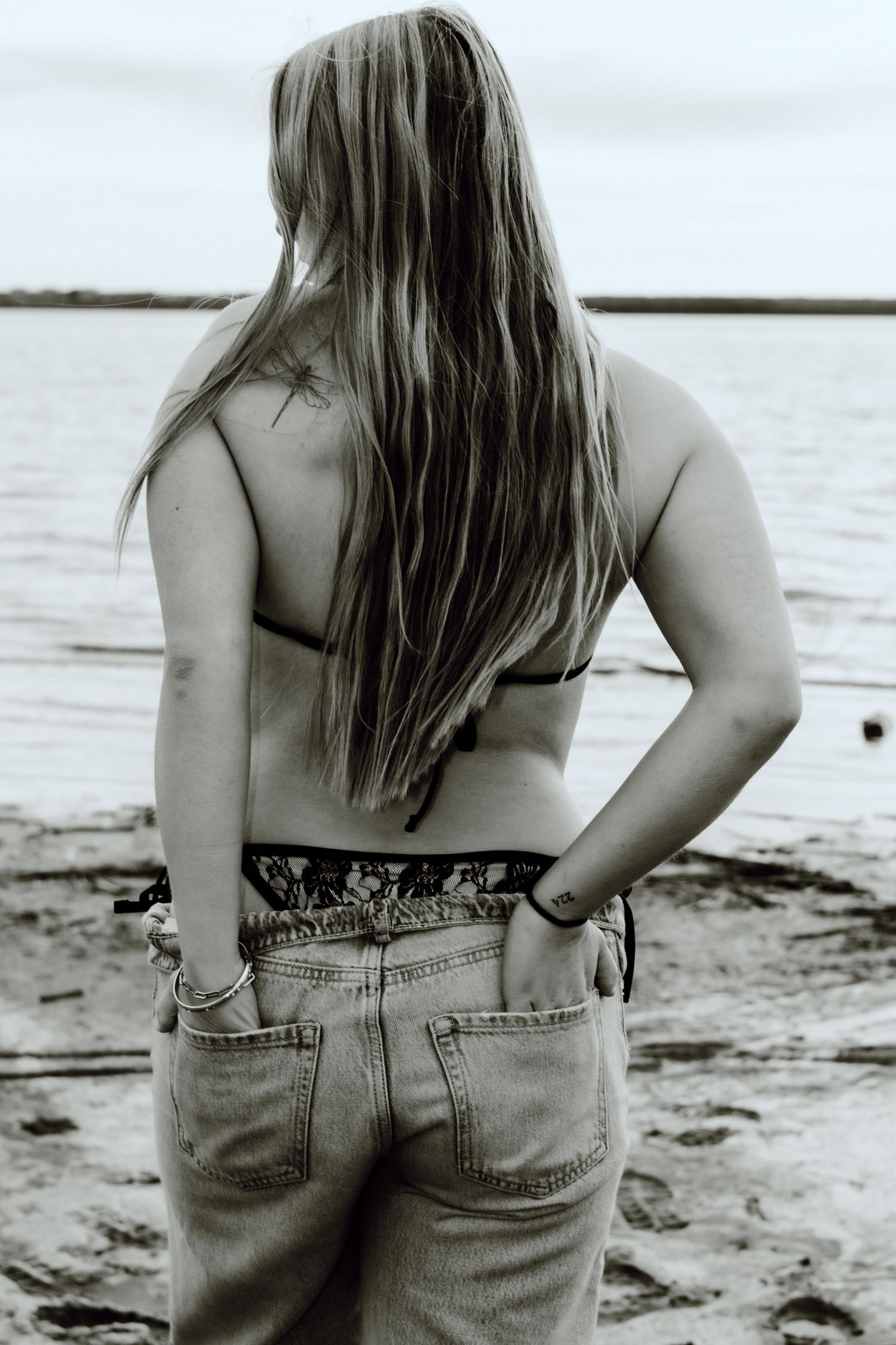 senior girl taking beach photos in swimsuit and jeans