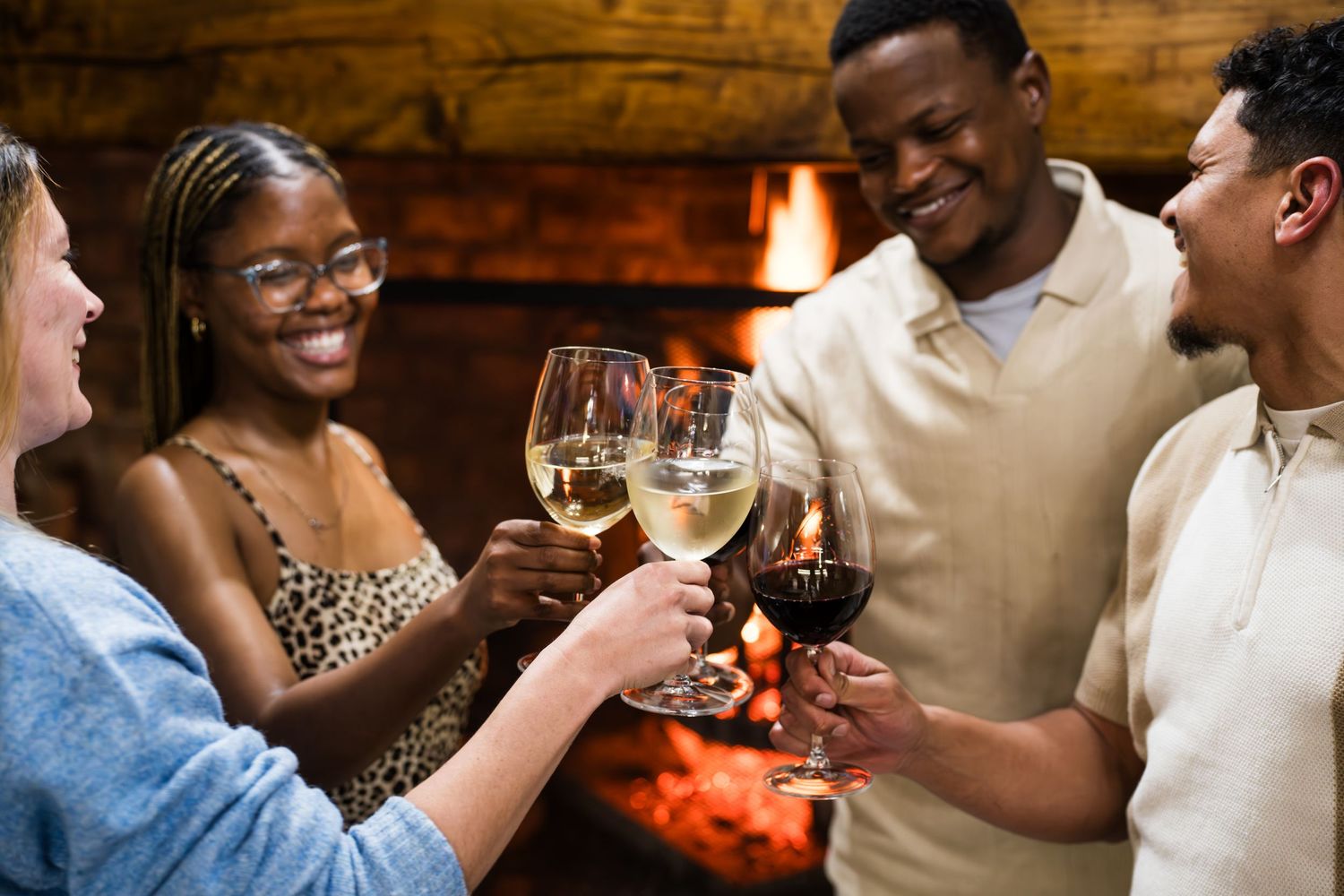 A group of young adults having a cheers in front of a fire