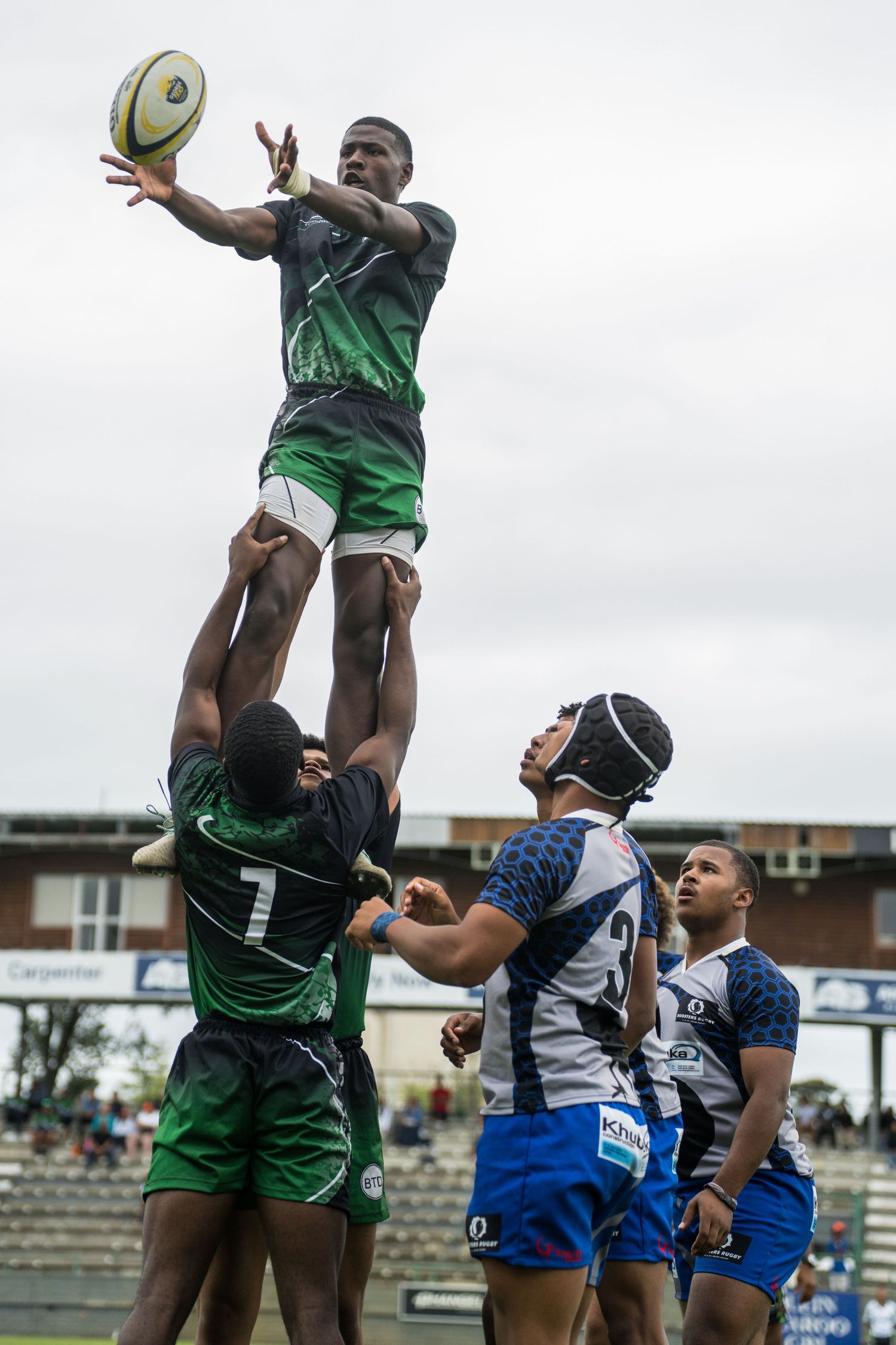 A rugby player catching the rugby ball suspended in the air by 2 team mates in George