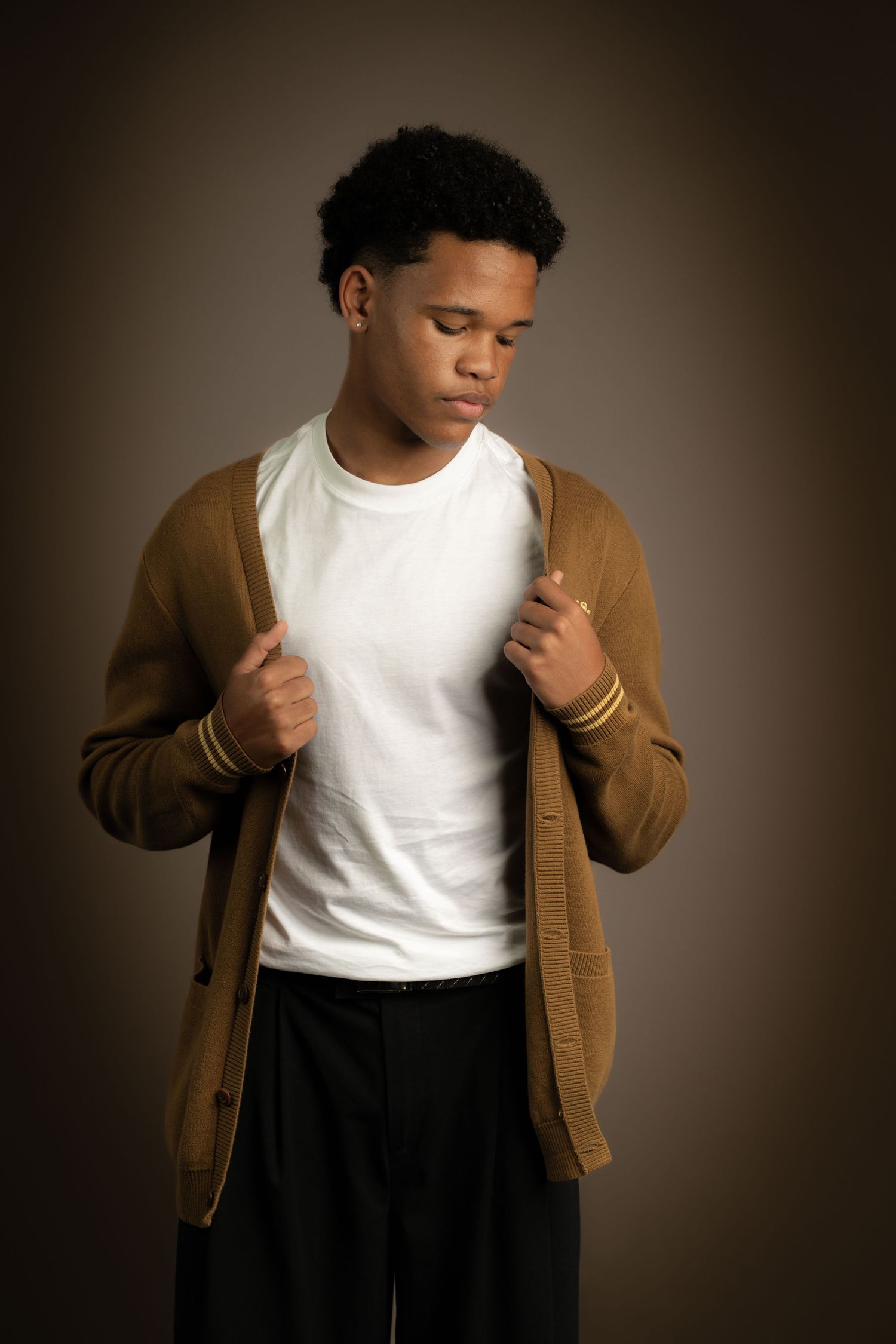 Studio portrait of a man wearing a white t-shirt and brown jacket