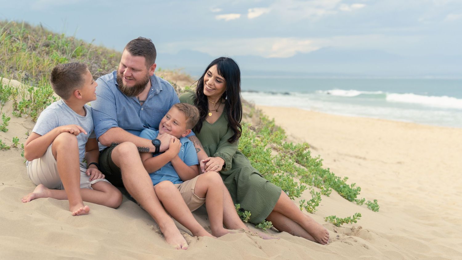 Family sitting together on a sandy beach during a lifestyle photoshoot