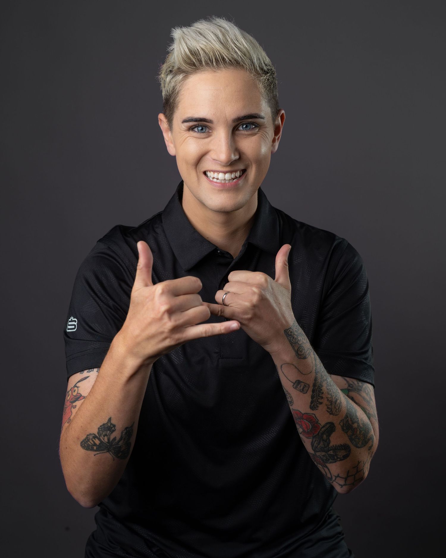 Studio portrait of a woman with short blonde hair making a hand gesture