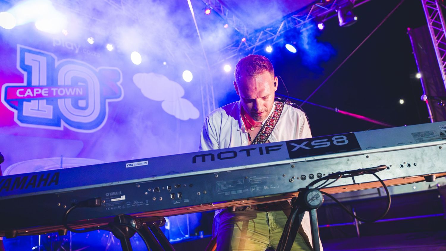 Musician playing a Yamaha Motif XS8 keyboard on a colorful stage at Cape Town 10 event.