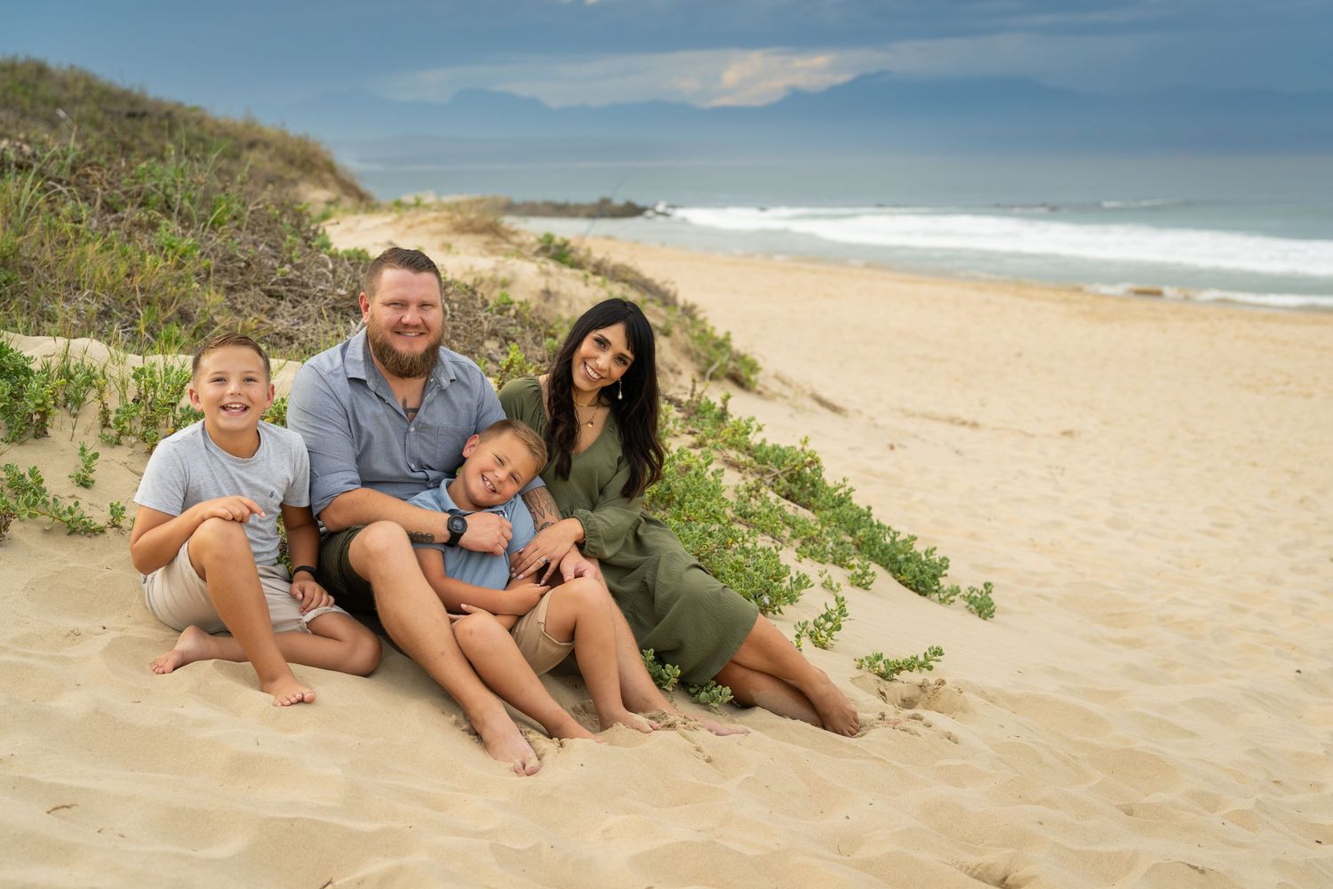 Family enjoying a sunny day together on a beautiful beach with waves in the background.