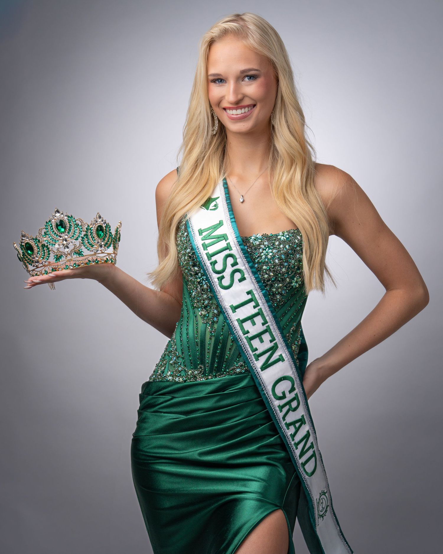 Beauty pageant contestant wearing an emerald green evening gown and crown with sash posing for glamour shots.