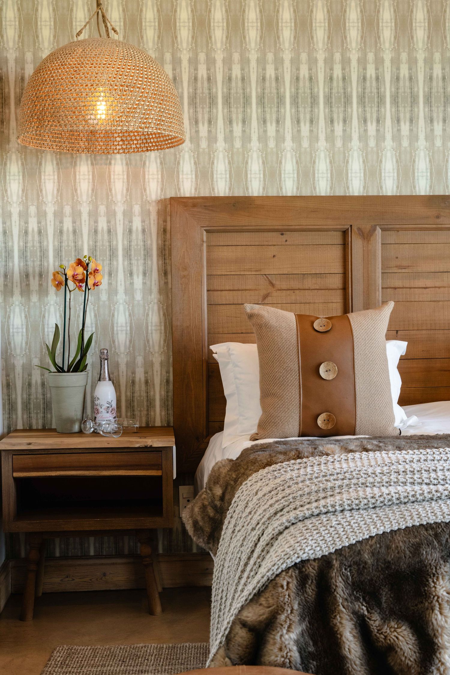 Closeup photo showing a bit of the bed and lamp and potted plant in a guest house