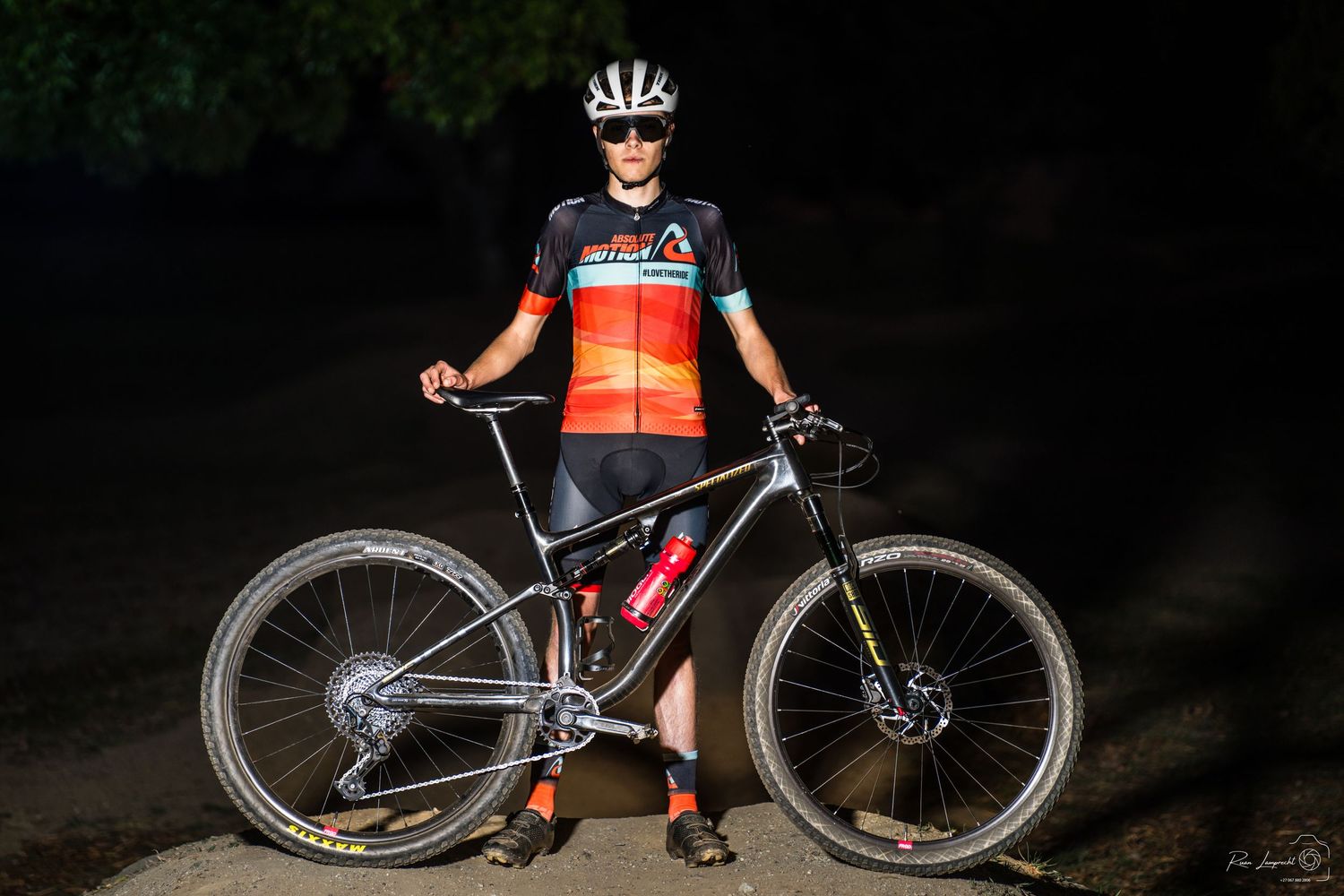Portrait of a professional cyclist at night with his bike in front of him