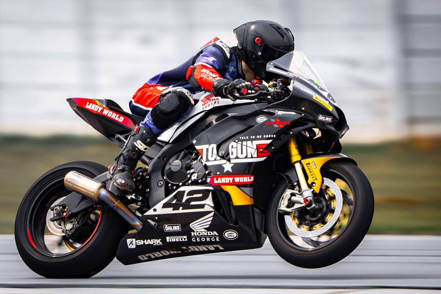 Motorcycle racer cornering at high speed and lifting his front wheel during a track racing event at Aldo Scribante Racetrack