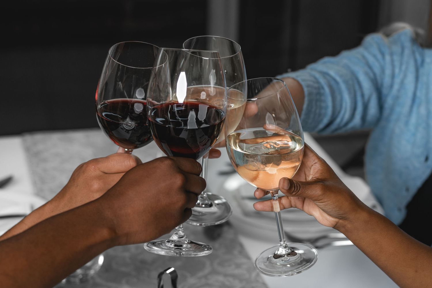 Wine glasses clinking together in a celebratory toast against dark background.