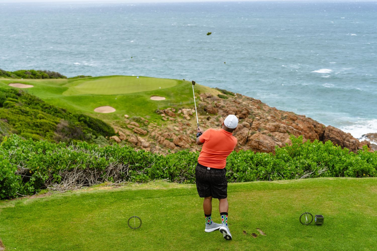 A golfer taking a swing at the iconic hole at pinnacle point in Mossel Bay