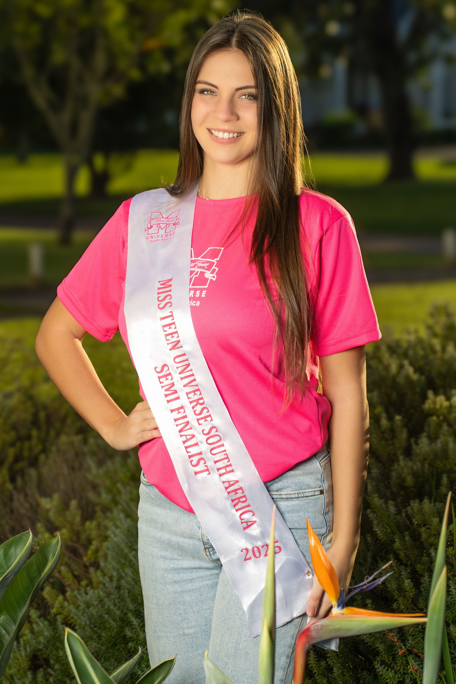 Young woman wearing a pink shirt and Miss Teen Universe South Africa 2025 Semi-Finalist sash outdoors.