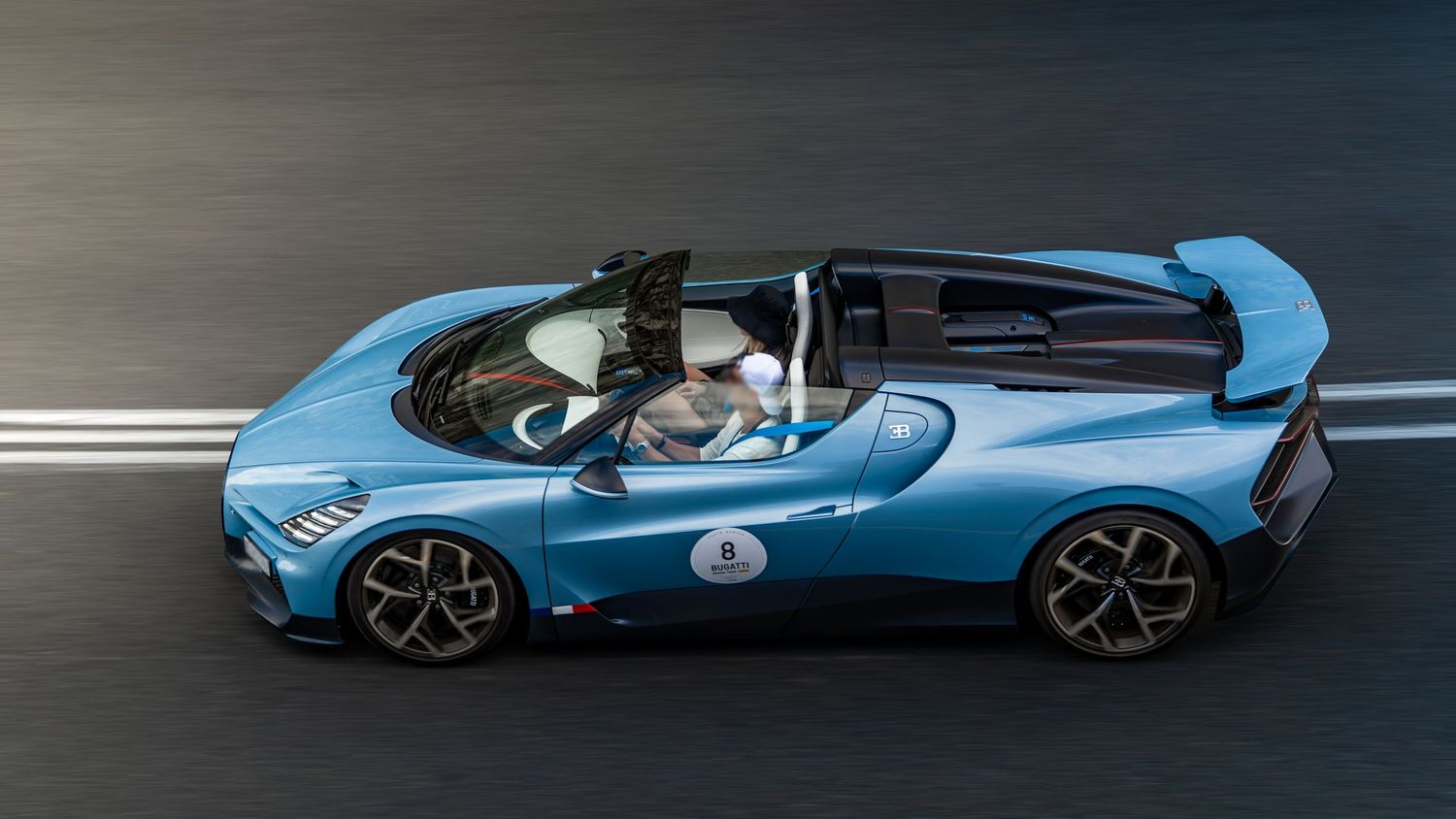 Light blue Bugatti Mistral open-top hypercar speeding on a track, showcasing its sleek aerodynamic design.