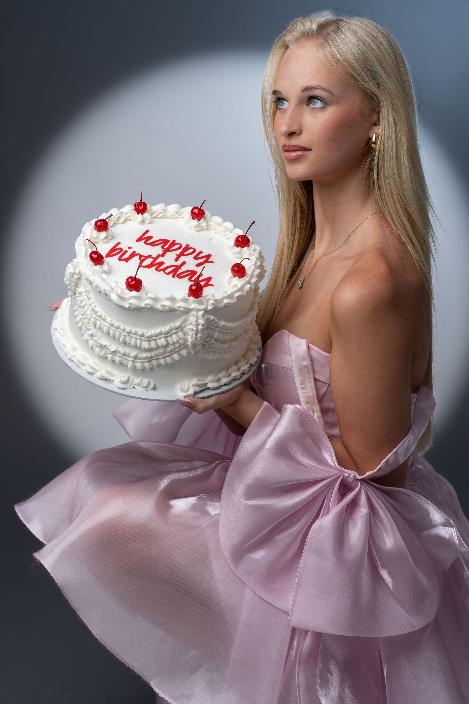 Woman holding a birthday cake wearing a pink tulle dress in studio