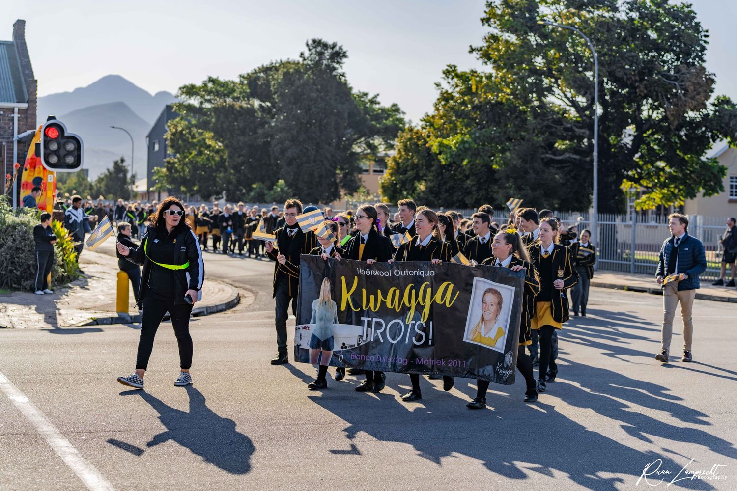 A wide shot showcasing a parade of a local highschool in george walking through the main streets