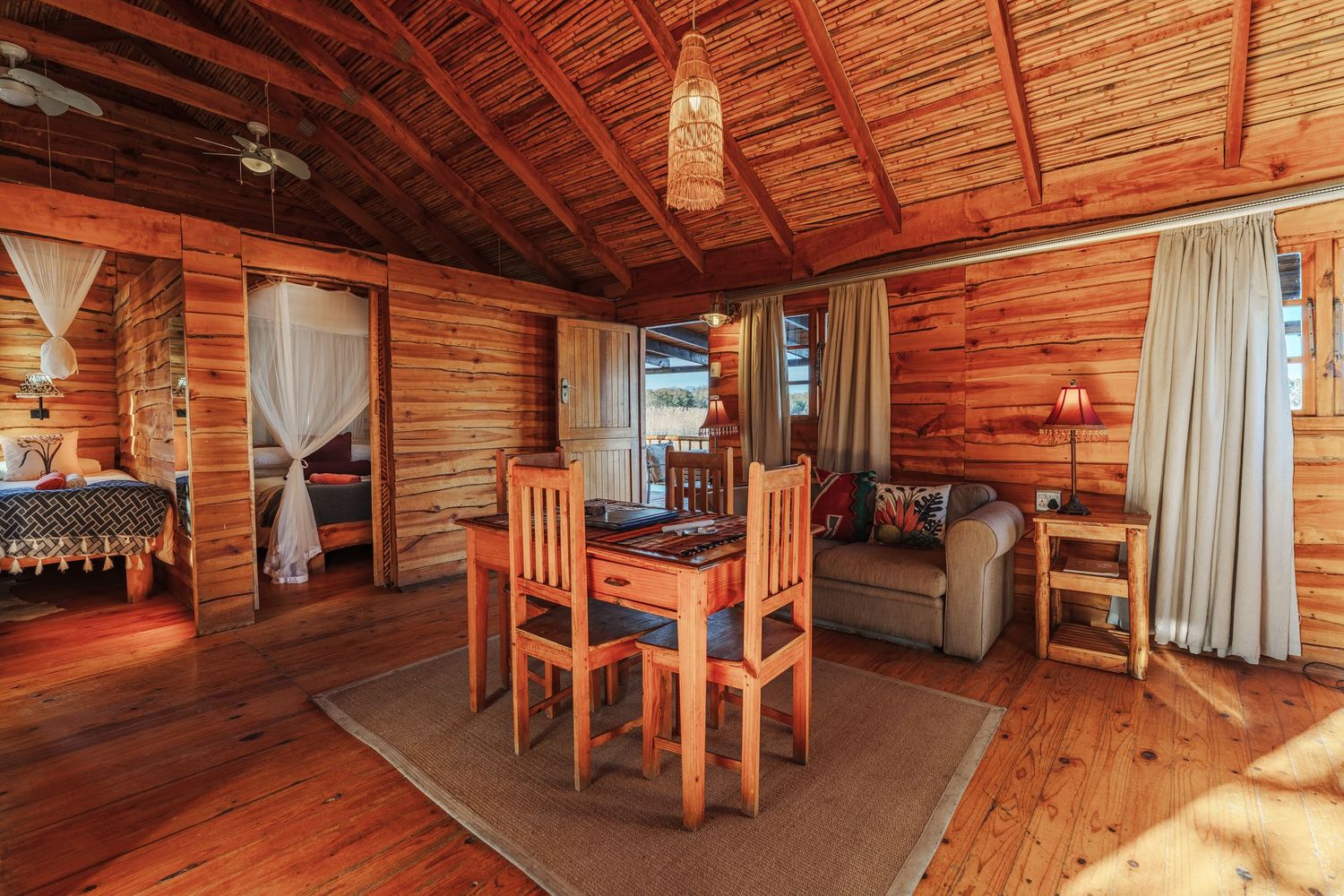 Interior of a rustic wooden cabin with 2 bedrooms and a living area overlooking a lake