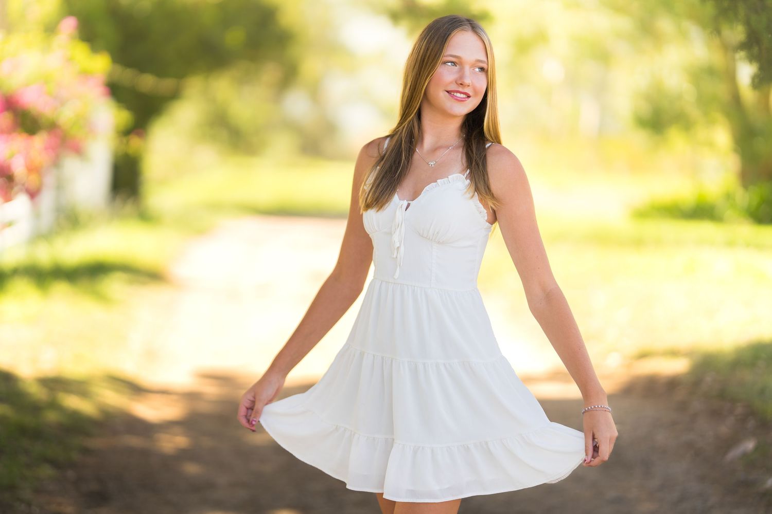 A person in a flowing white sundress twirls outdoors in soft golden sunlight with a blurred natural background.