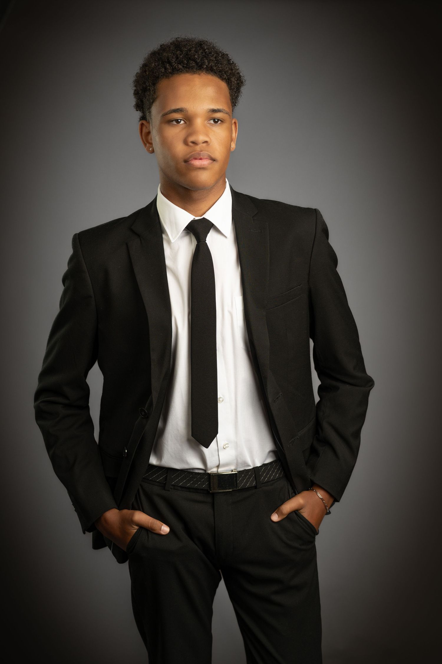 Studio portrait of a man in a black suit on a grey backdrop, photographed in George, South Africa