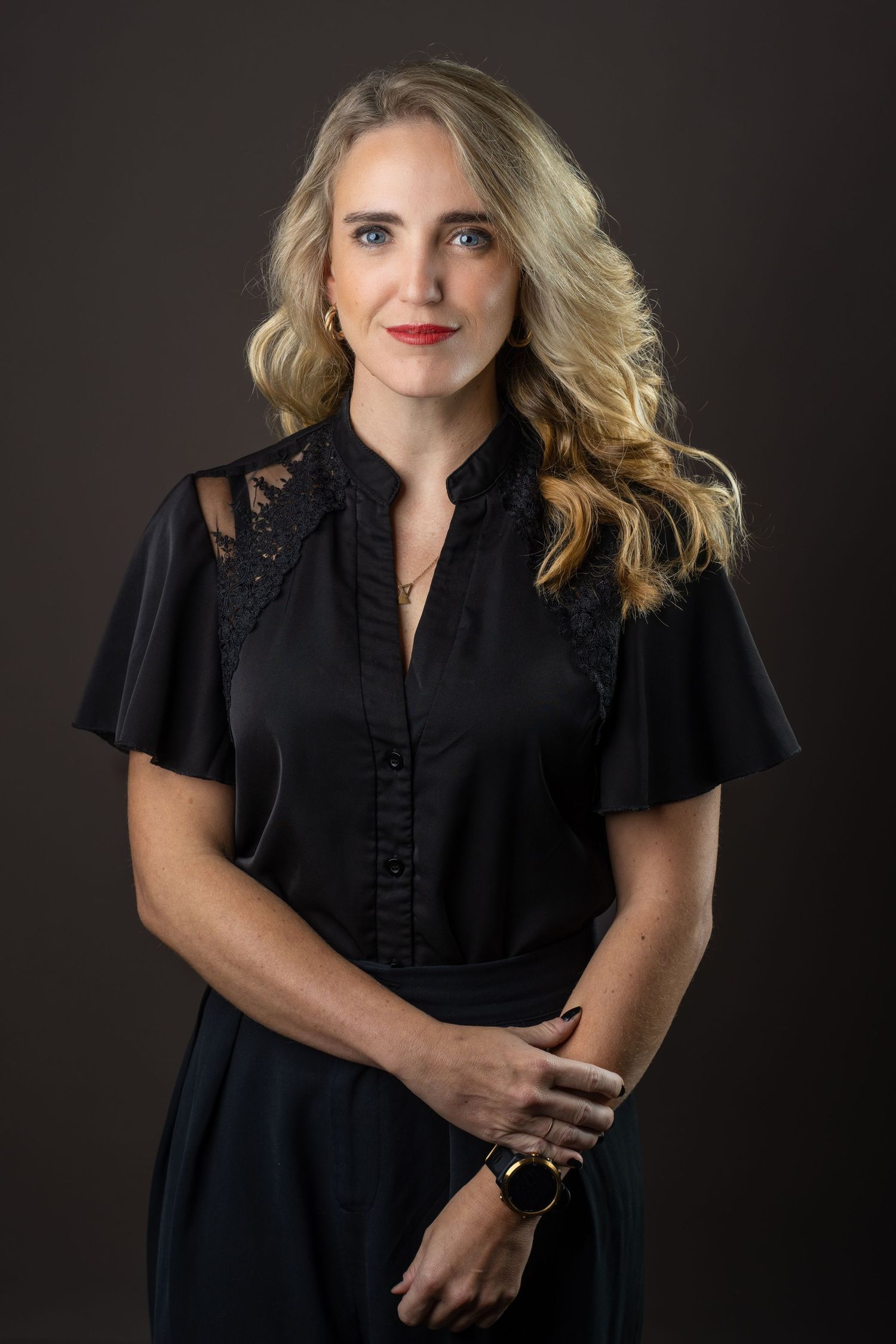 Studio portrait of woman in black dress against dark background.