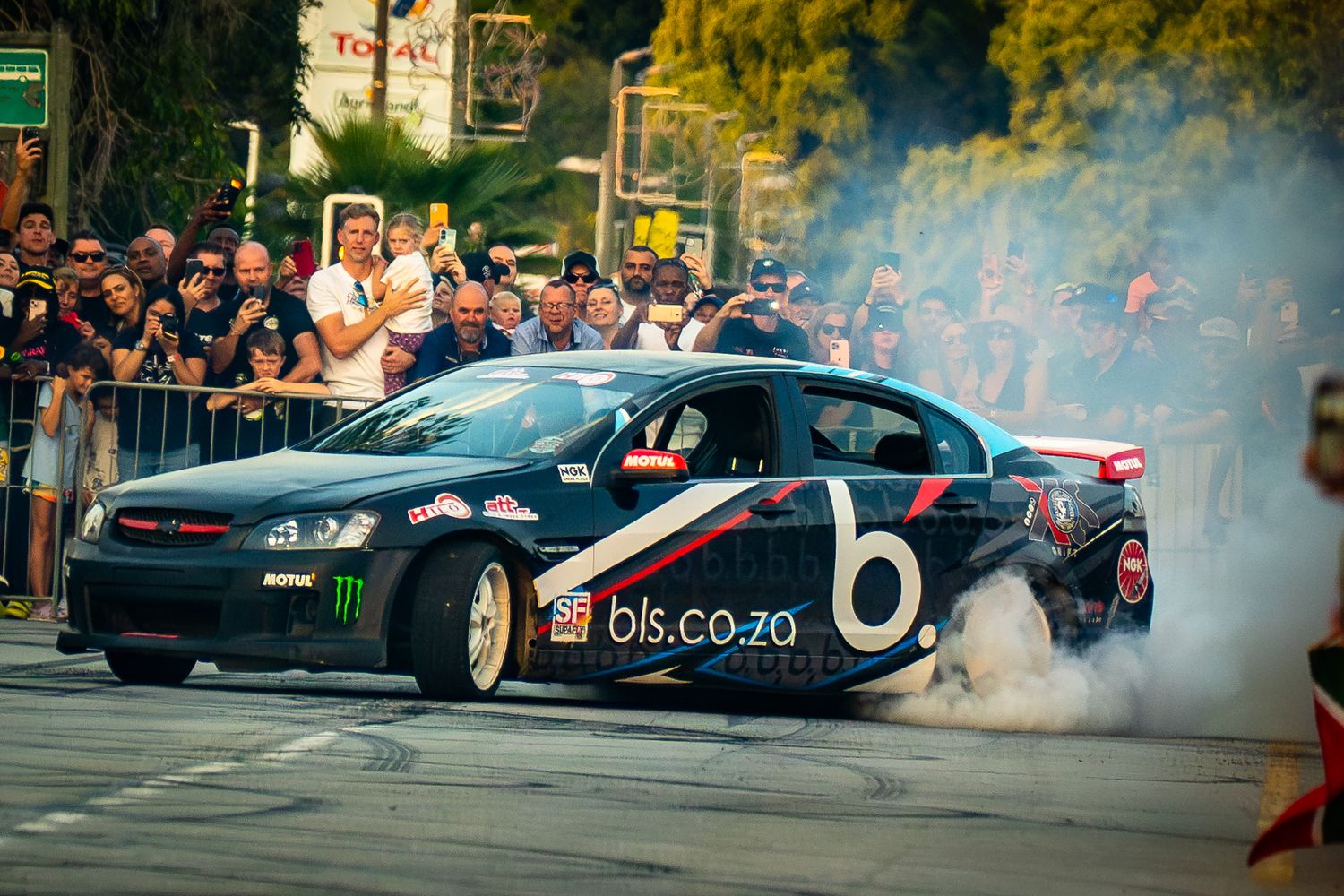 Race car performing a burnout during the Simola Hillclimb with spectators watching