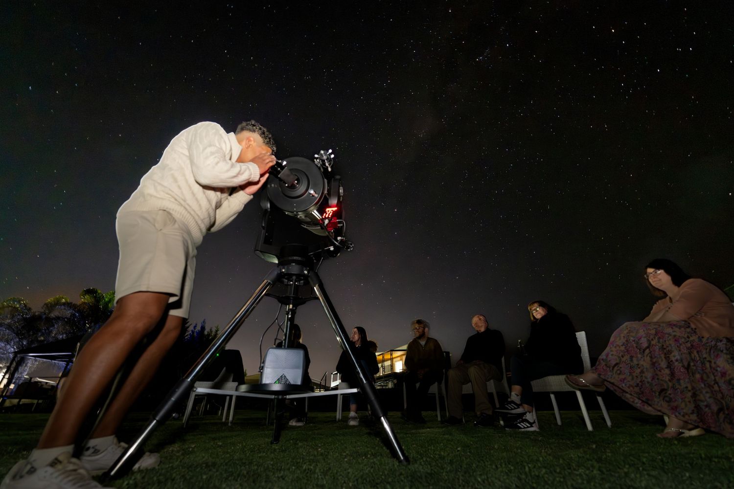 A young adult stargazing though a big telescope