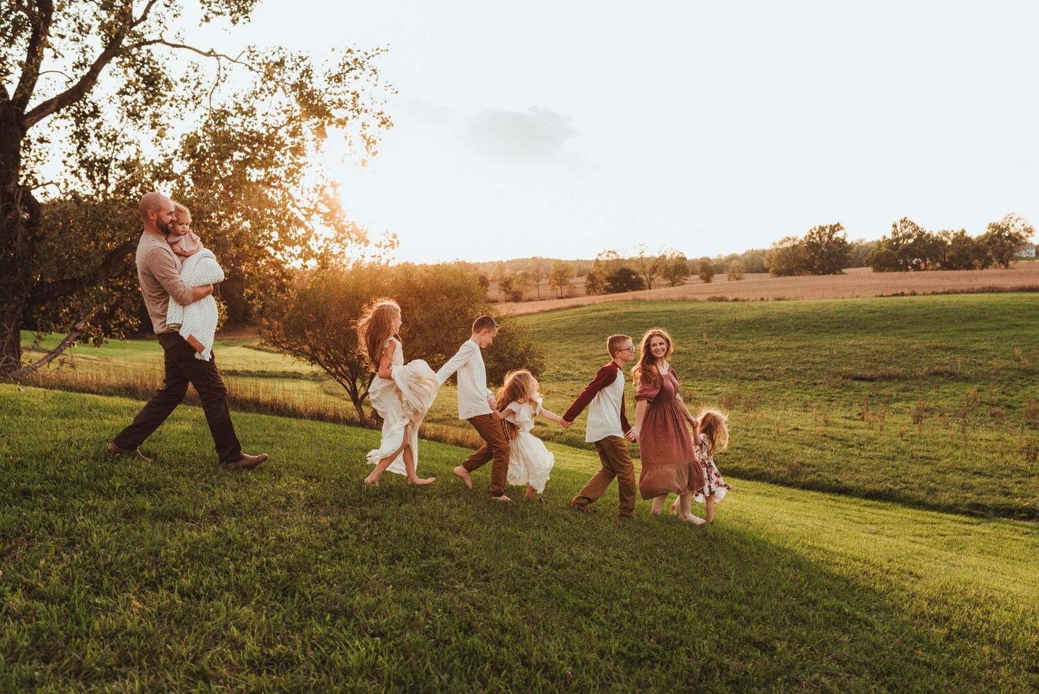 A happy family playing and running together across a lush green lawn during golden sunset.