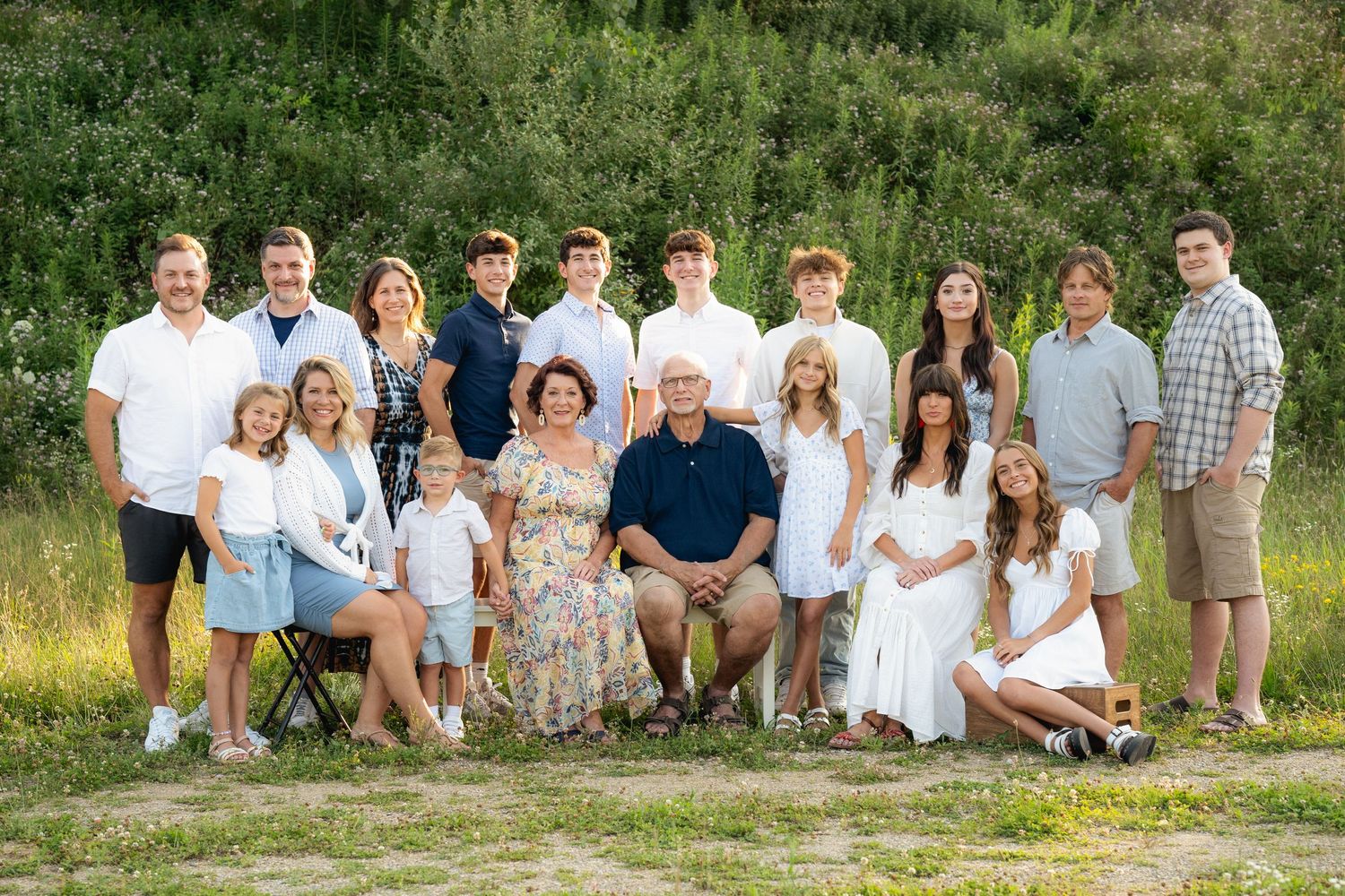 Large extended family posing together outdoors in a green natural setting.