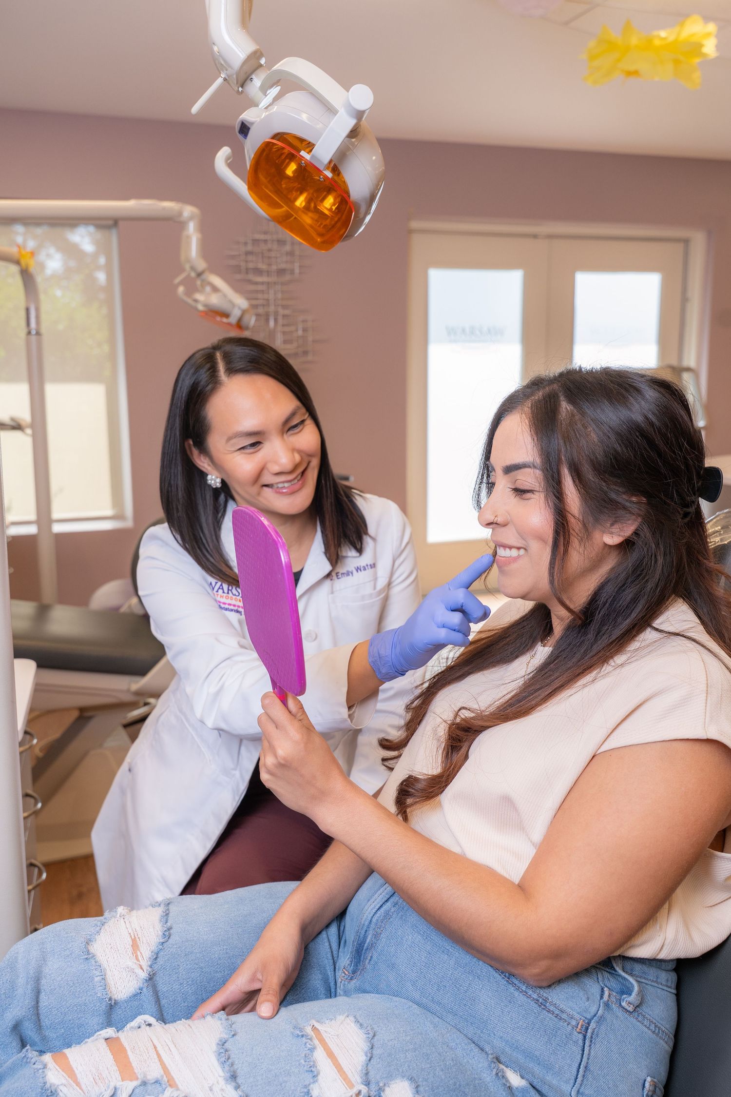 Dental professional showing patient results in mirror during cosmetic dental consultation.