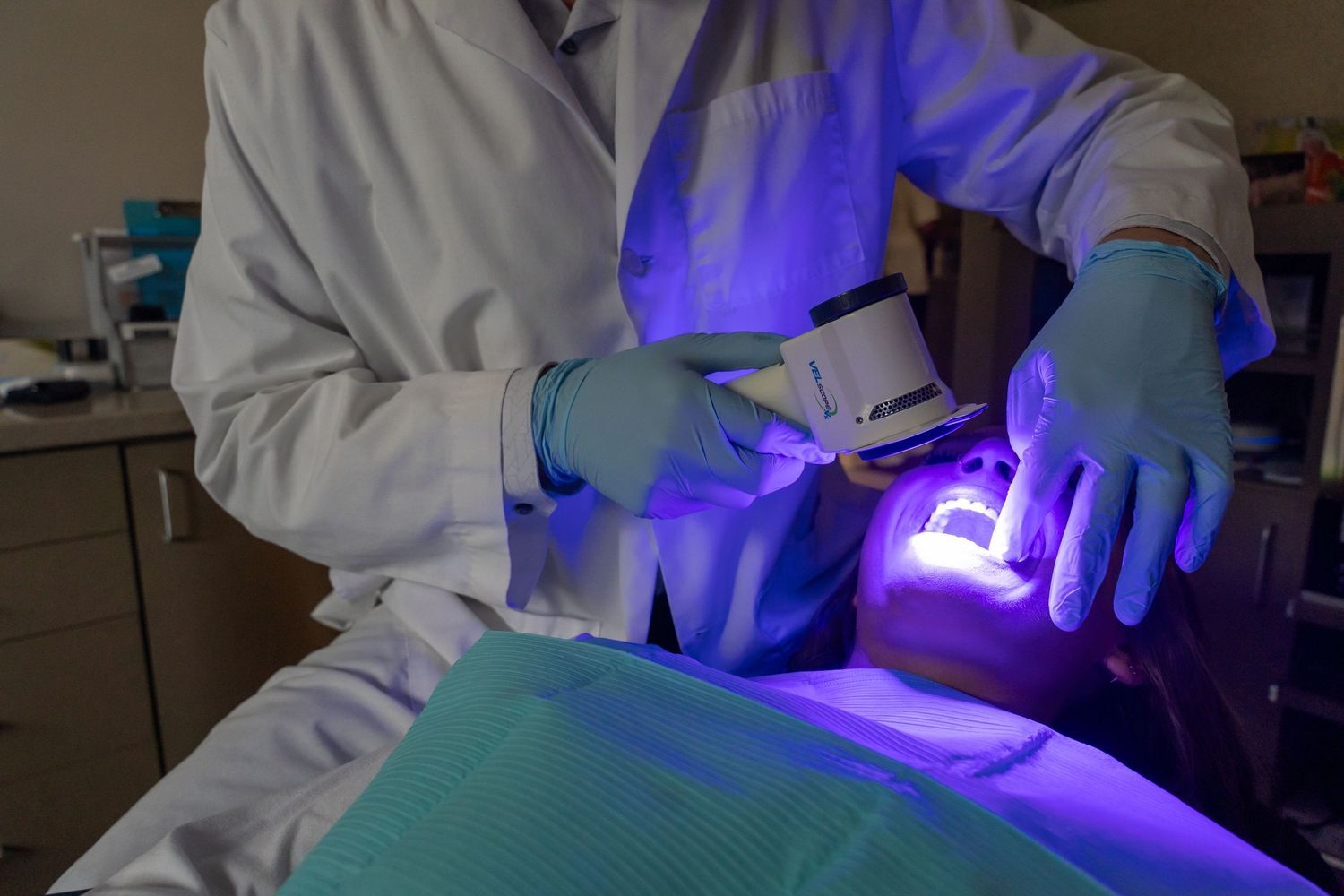 A medical professional uses UV light device on a patient during a clinical procedure.