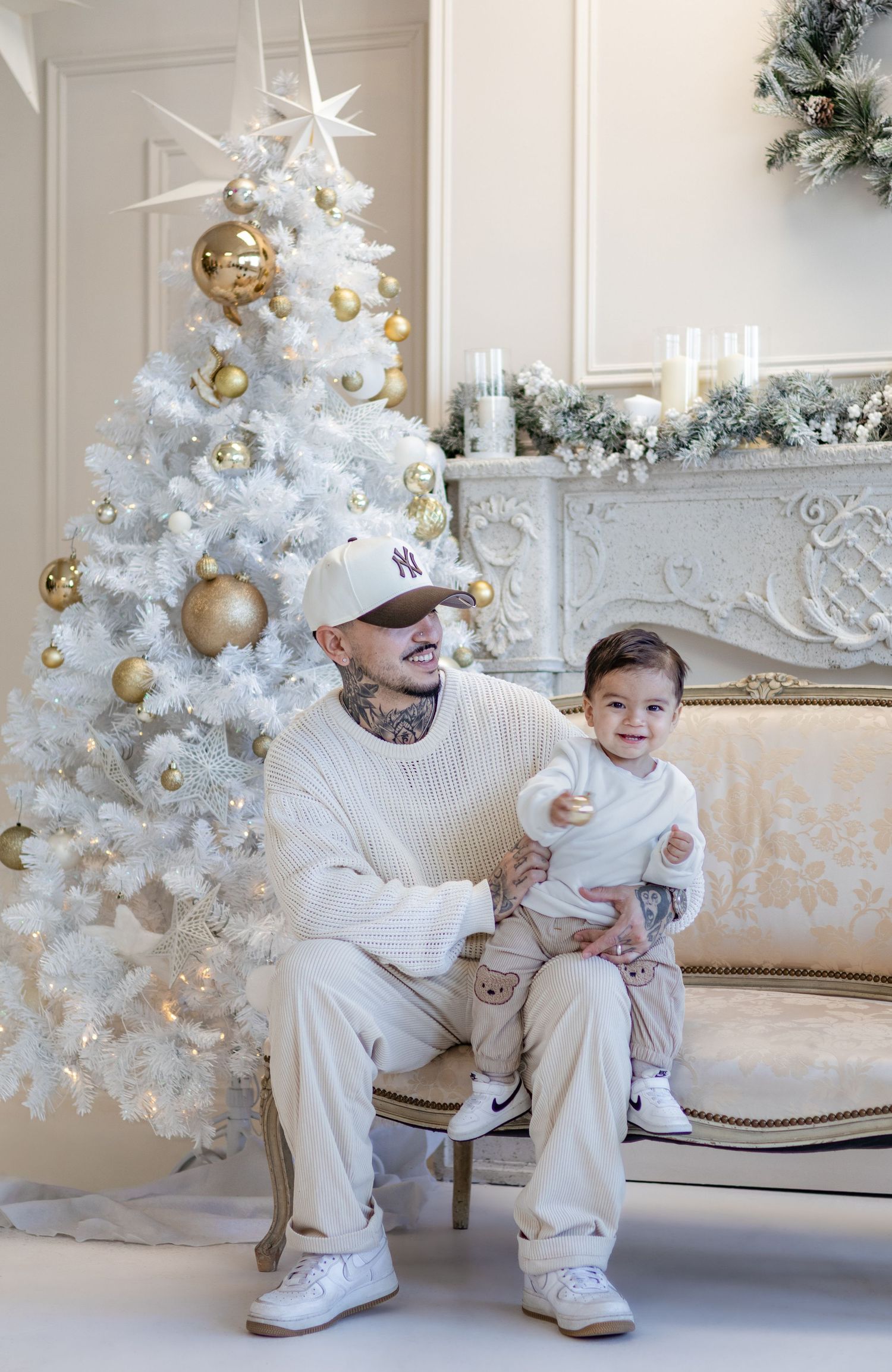 White Christmas themed family portrait session with decorated tree and elegant furniture.