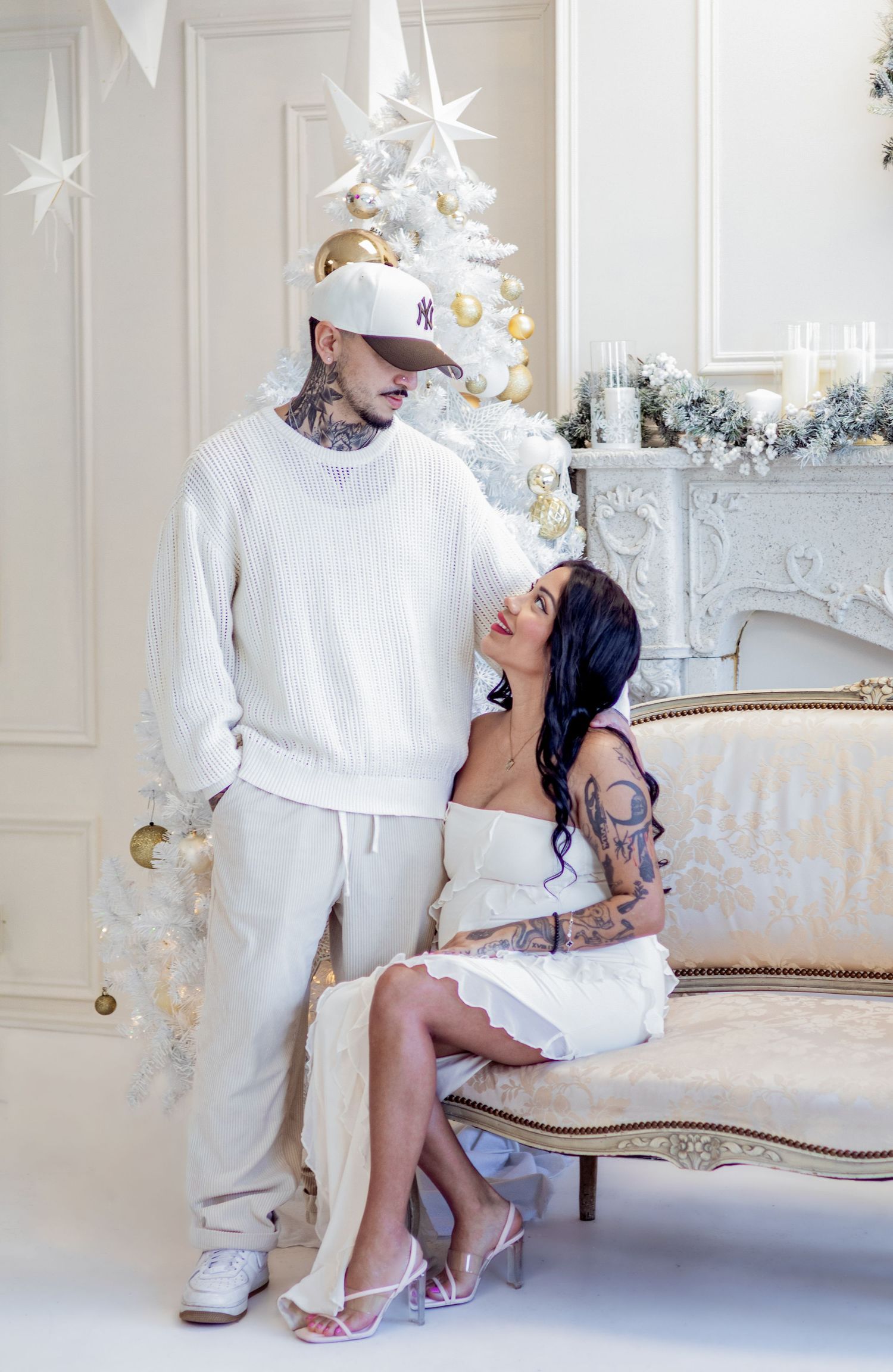 Intimate family holiday photos on vintage couch with white Christmas tree and gold ornaments.