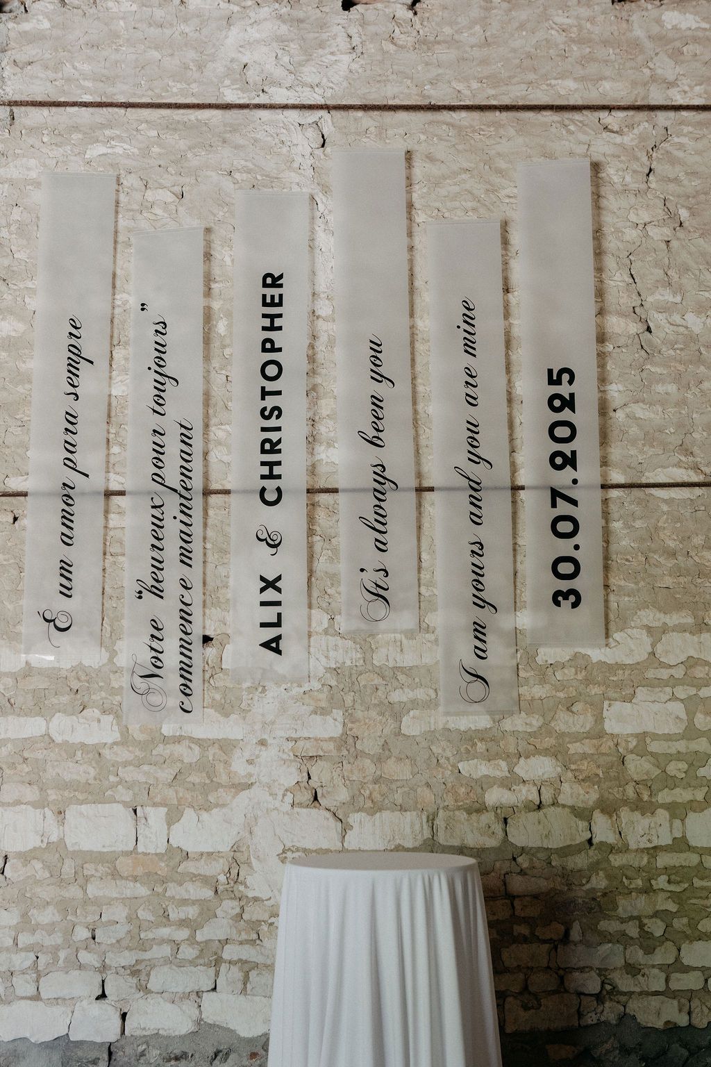 Wedding signage with couple names Alix and Christopher and date 30.07.2025 on rustic stone wall.