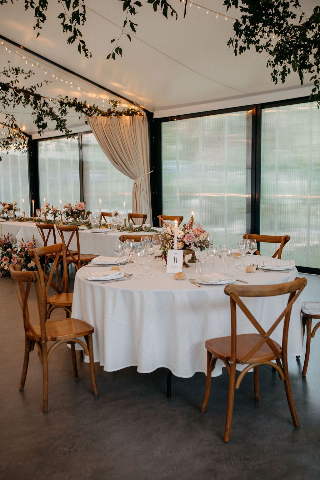 Wedding reception table set with white linen, glassware, candles and blush floral centerpieces.