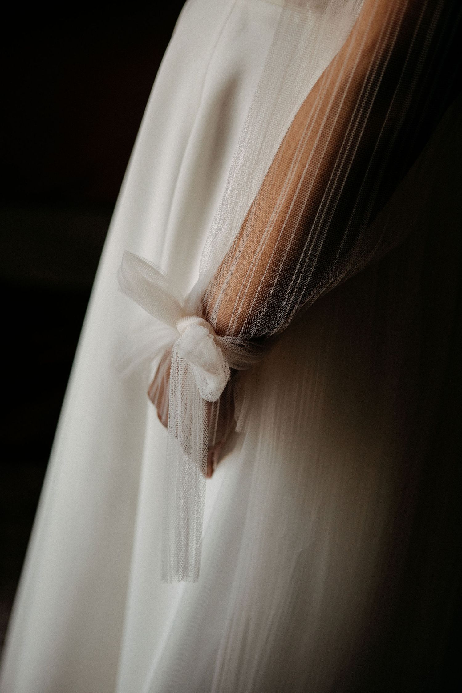 Close-up detail of delicate tulle bow on back of white wedding dress.