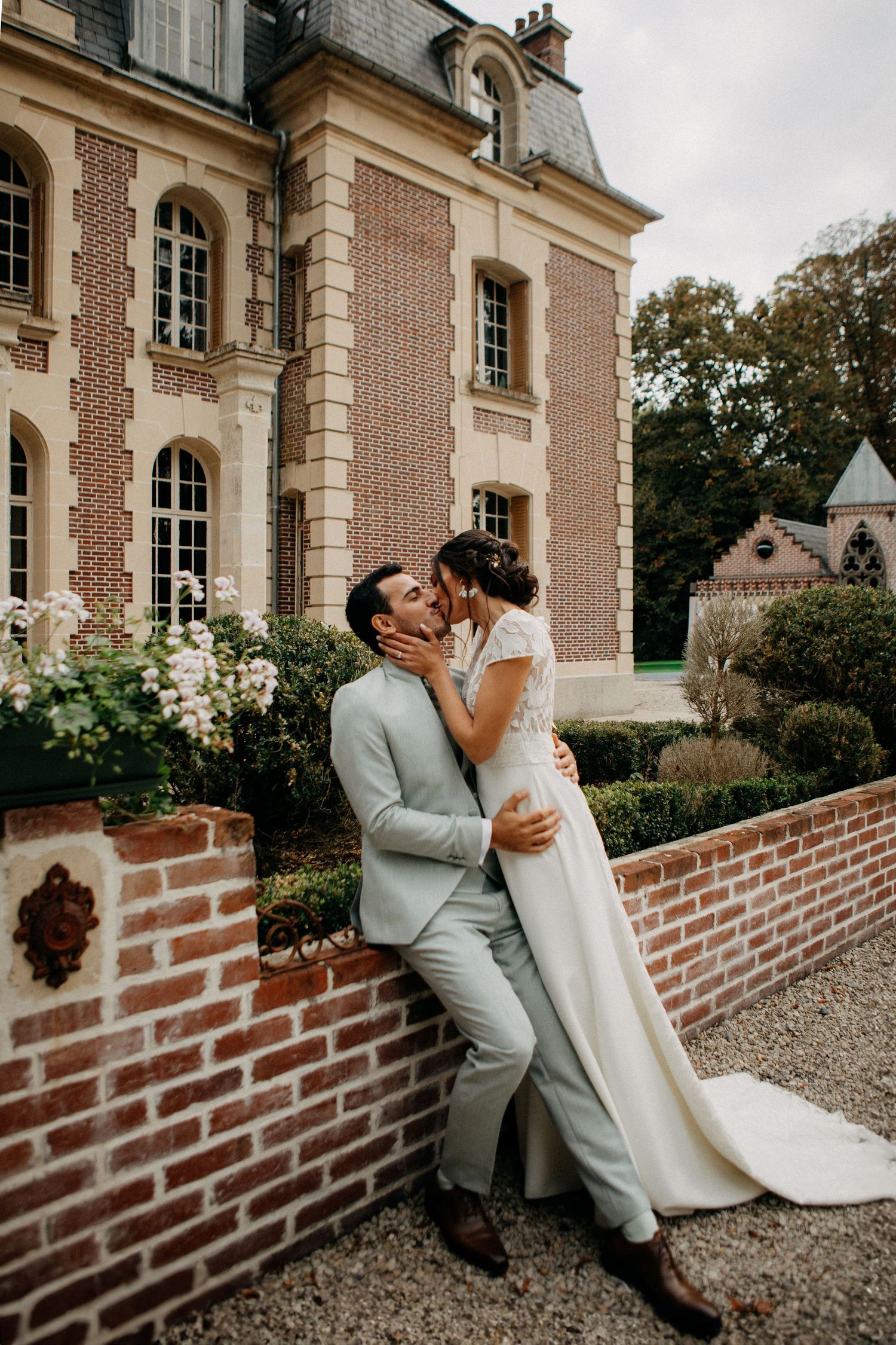 Bride and groom share a romantic kiss outside a grand French chateau wedding venue.
