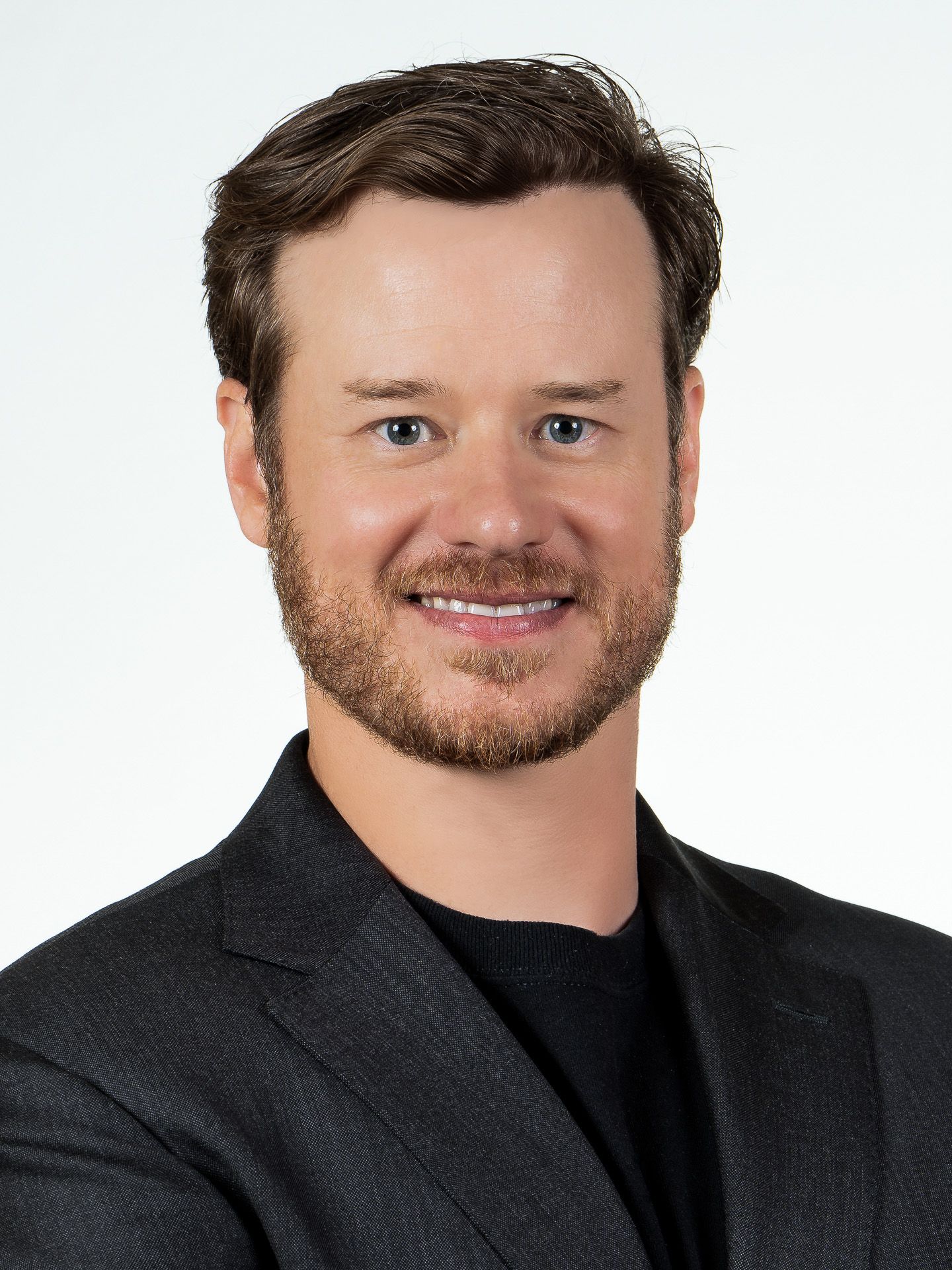 Studio headshots showing different angles in dark jacket against white background.