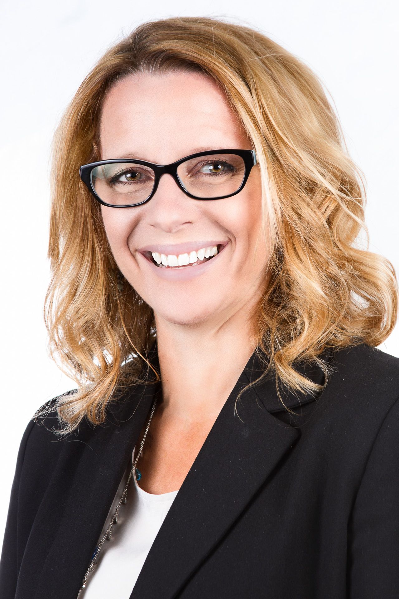 Professional headshots in black blazer with blonde hair against white backdrop.