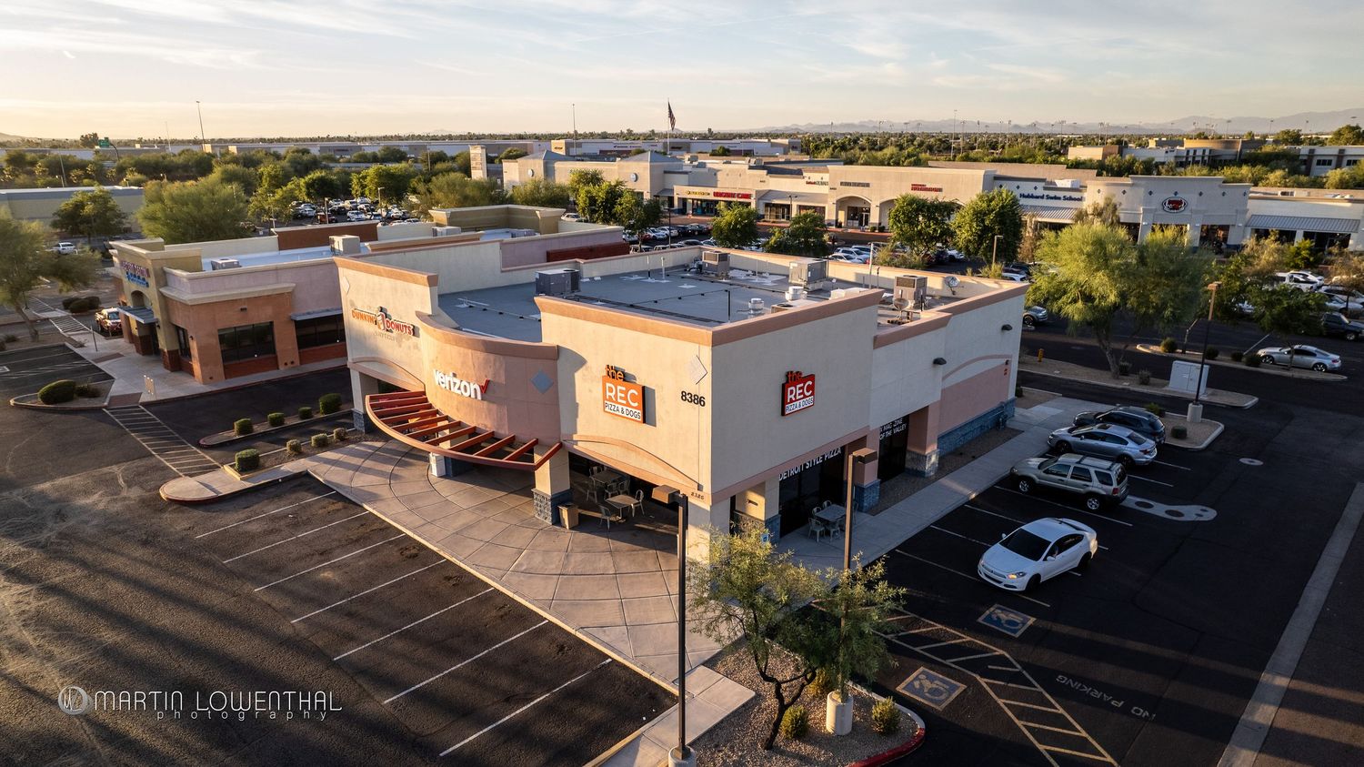 Aerial view of commercial buildings and parking lots in a suburban shopping center.