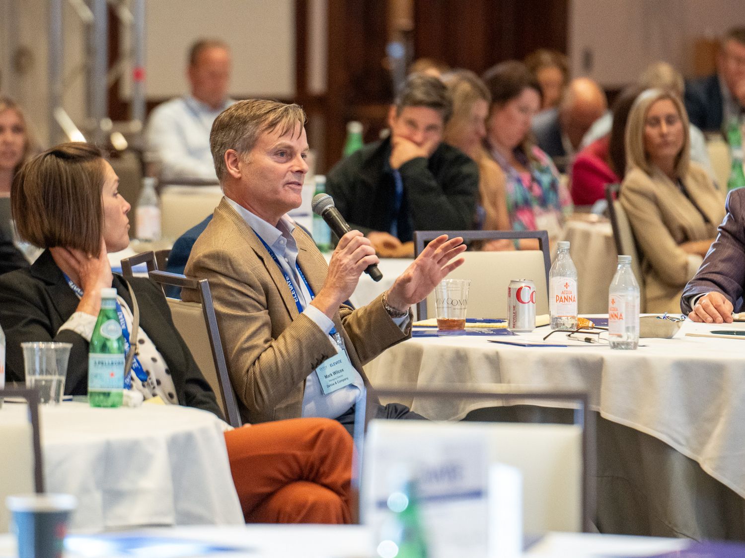Business conference attendees seated at round tables during formal event.