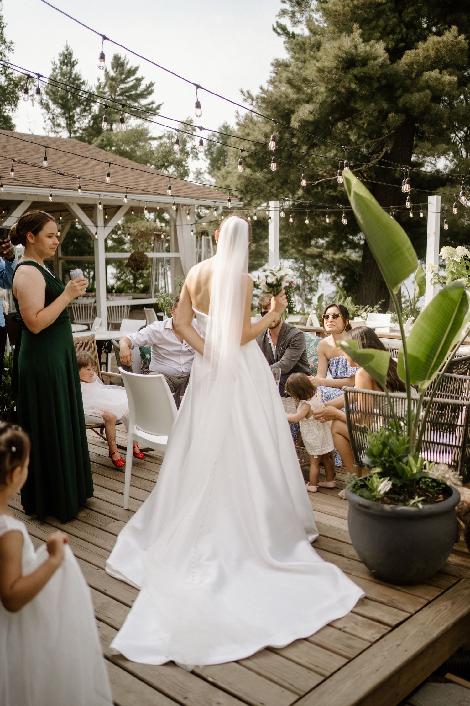 A series of photos showing a wedding dress being steamed and prepared on a wooden deck with tropical plants.