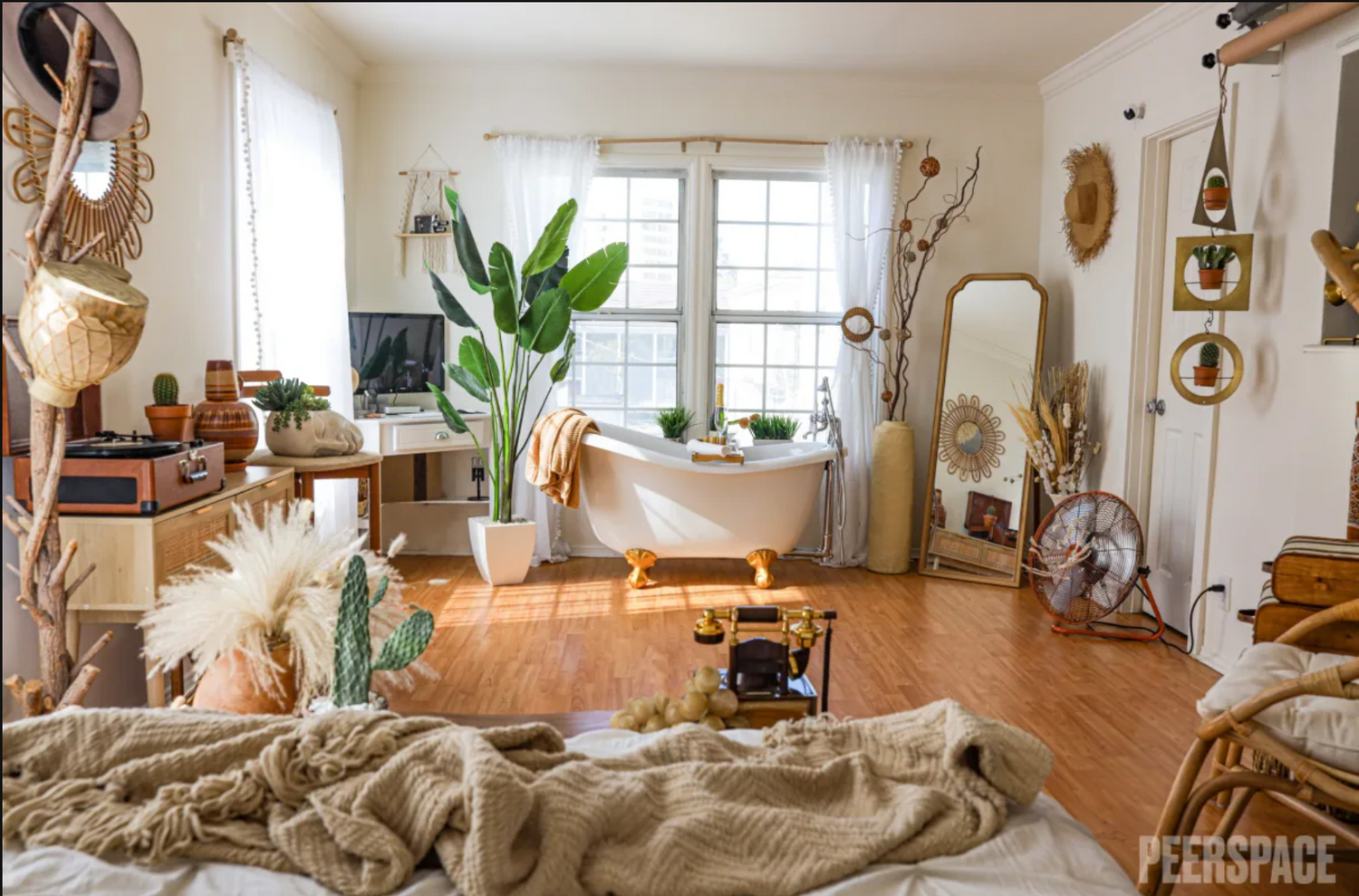 Cozy boho-style bedroom with hardwood floors, natural light, houseplants, and vintage decor elements throughout.