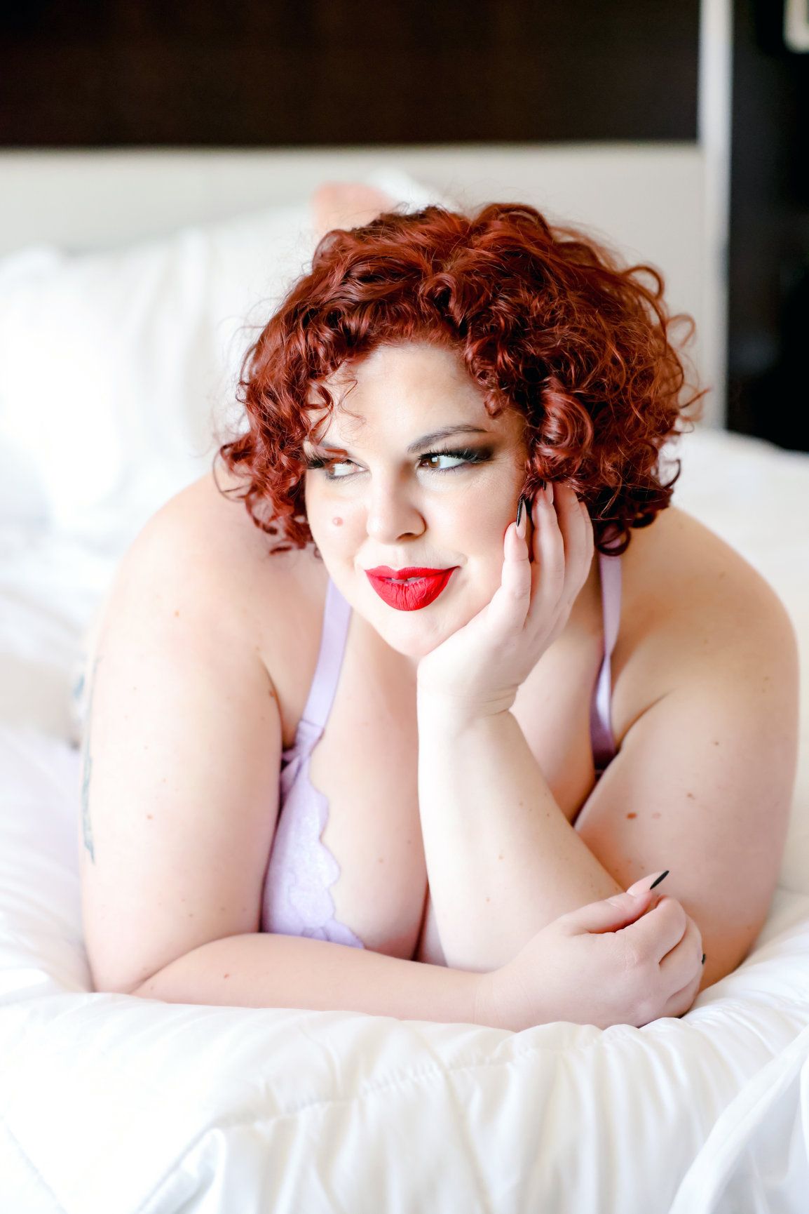 Boudoir portrait with curly red hair and classic glamour makeup.