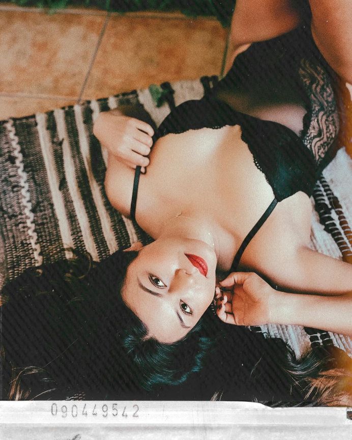 Intimate boudoir portrait with black lace lingerie on striped textile.