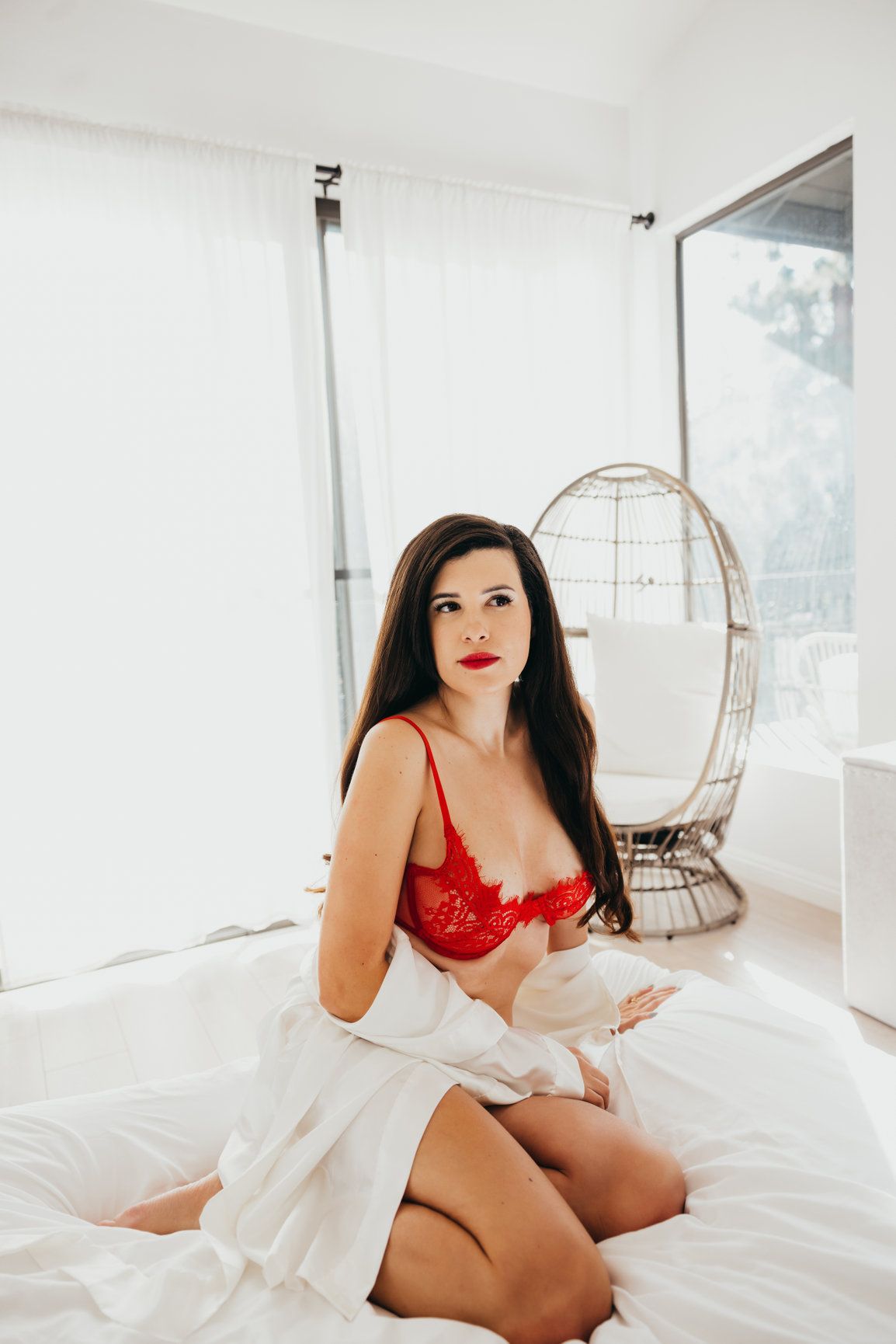 Boudoir photoshoot in white room with hanging chair and red lingerie.
