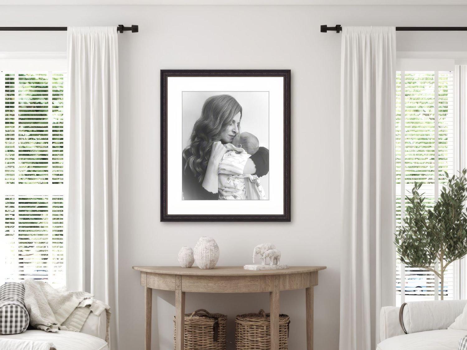 A luxury framed black and white photograph by a Lancaster, PA photographer hangs above a wooden console table between two curtained windows.