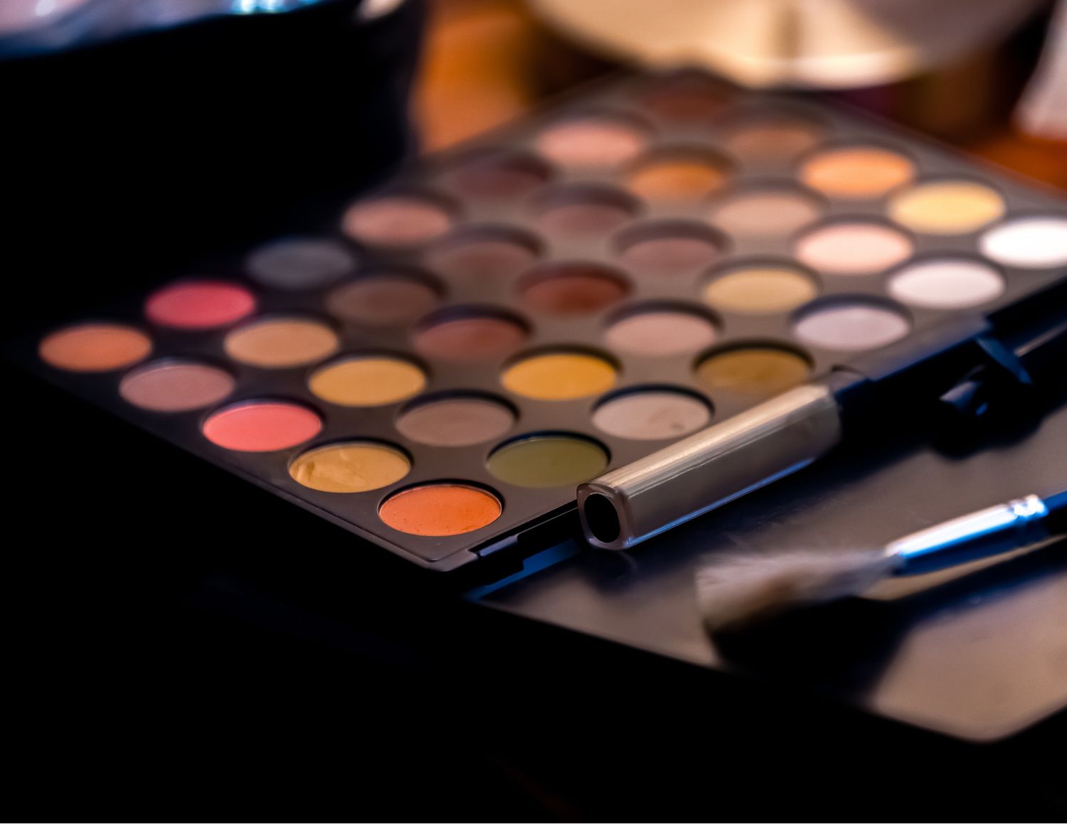 Professional makeup palette with colorful eyeshadow shades and brushes shown in close-up detail.