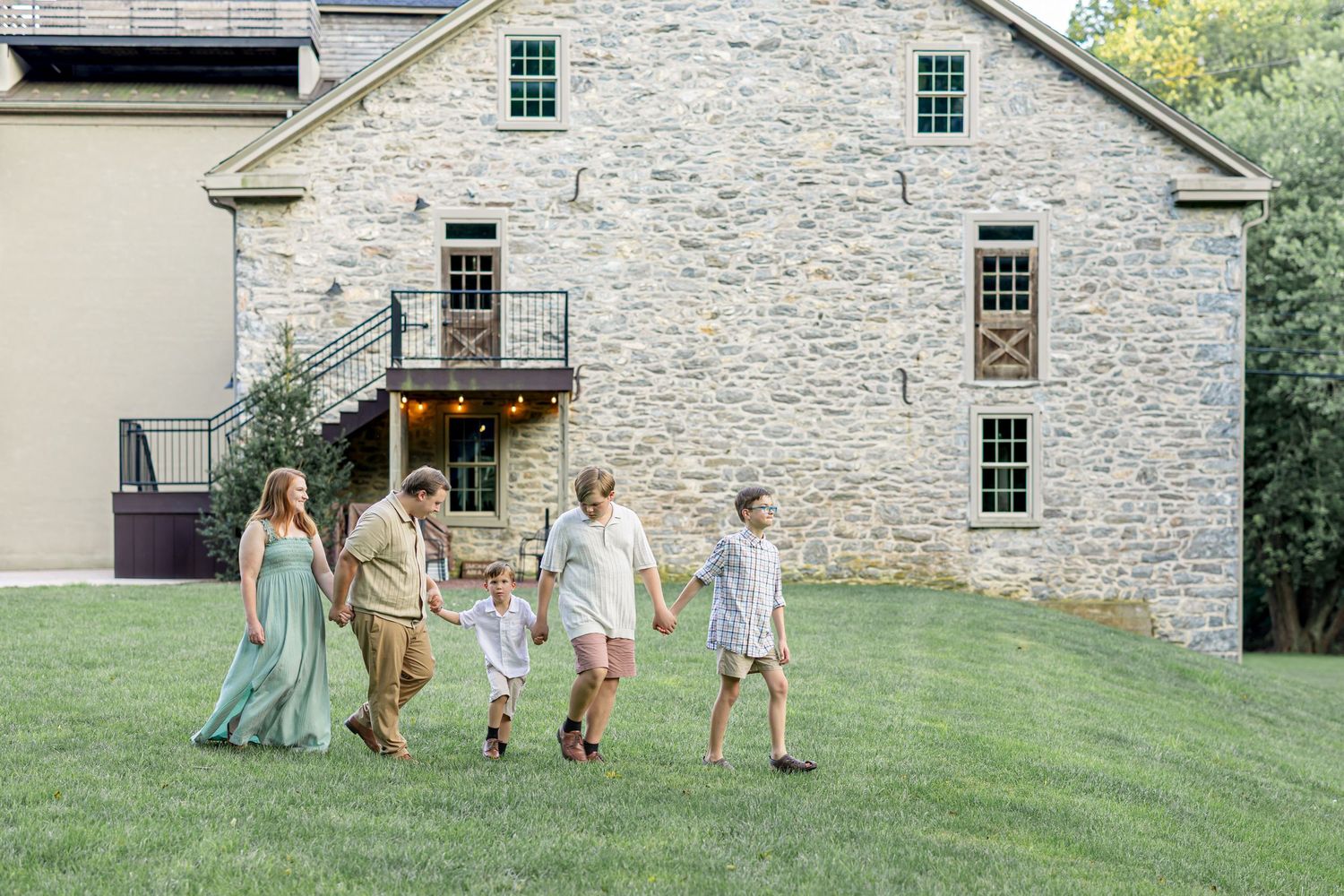 Family photo session in front of a rustic stone building with people wearing coordinated mint and neutral colors.