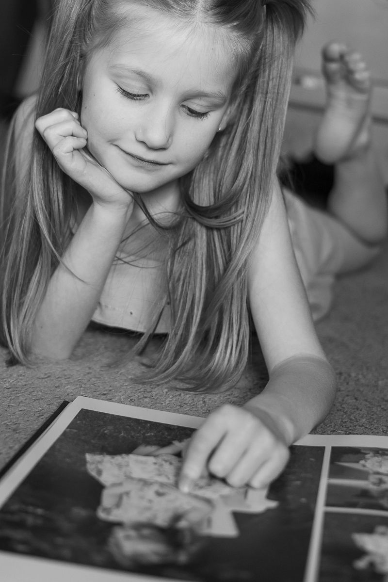 A little girl is enjoying looking at a family photography heirloom album.