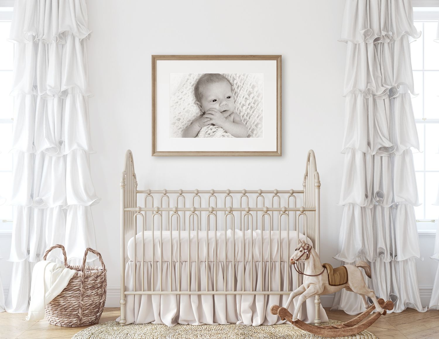 Neutral nursery room with white crib, ruffled curtains, woven basket, and framed artwork above the bed.
