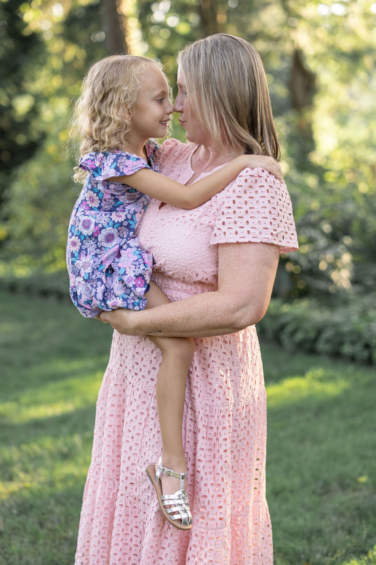 A Lancaster, PA family photographer captures a sweet moment between mother and daughter as they touch noses surrounded by lush greenery.
