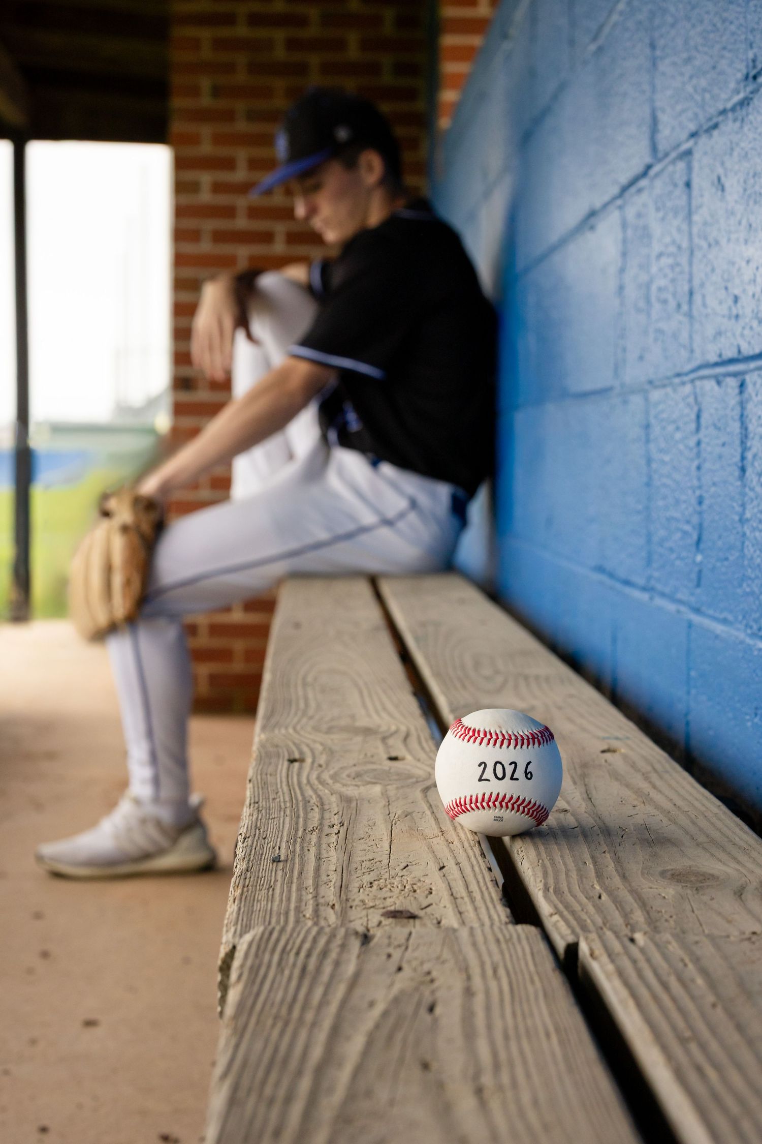 Artistic portrait of high school senior baseball player sitting in the dugout | Luxury senior portraits by Megan Mariah Photography